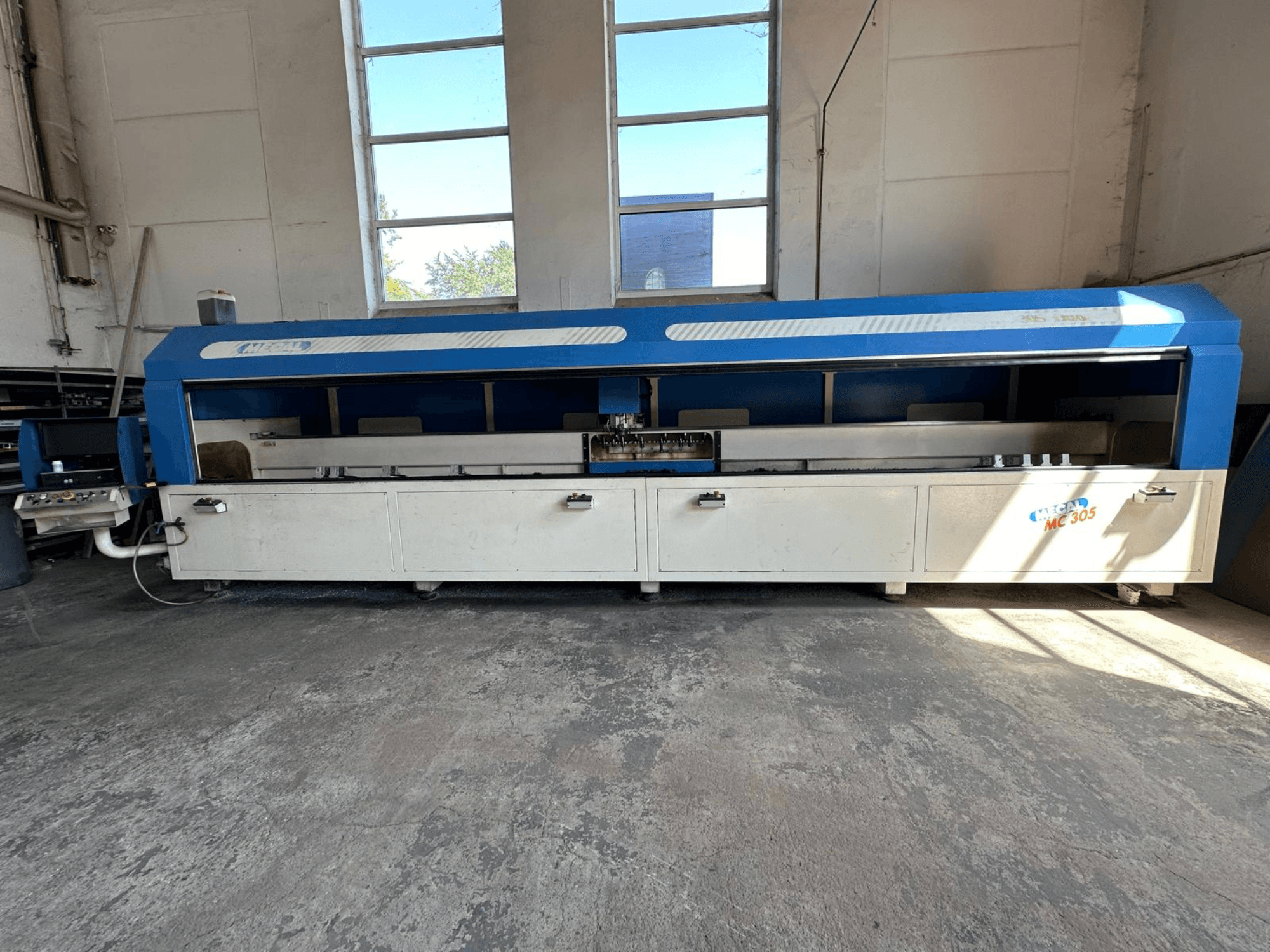 Front view of MECAL MC 305 vertical machining centre, featuring a blue and white design, visible work table and control panel.