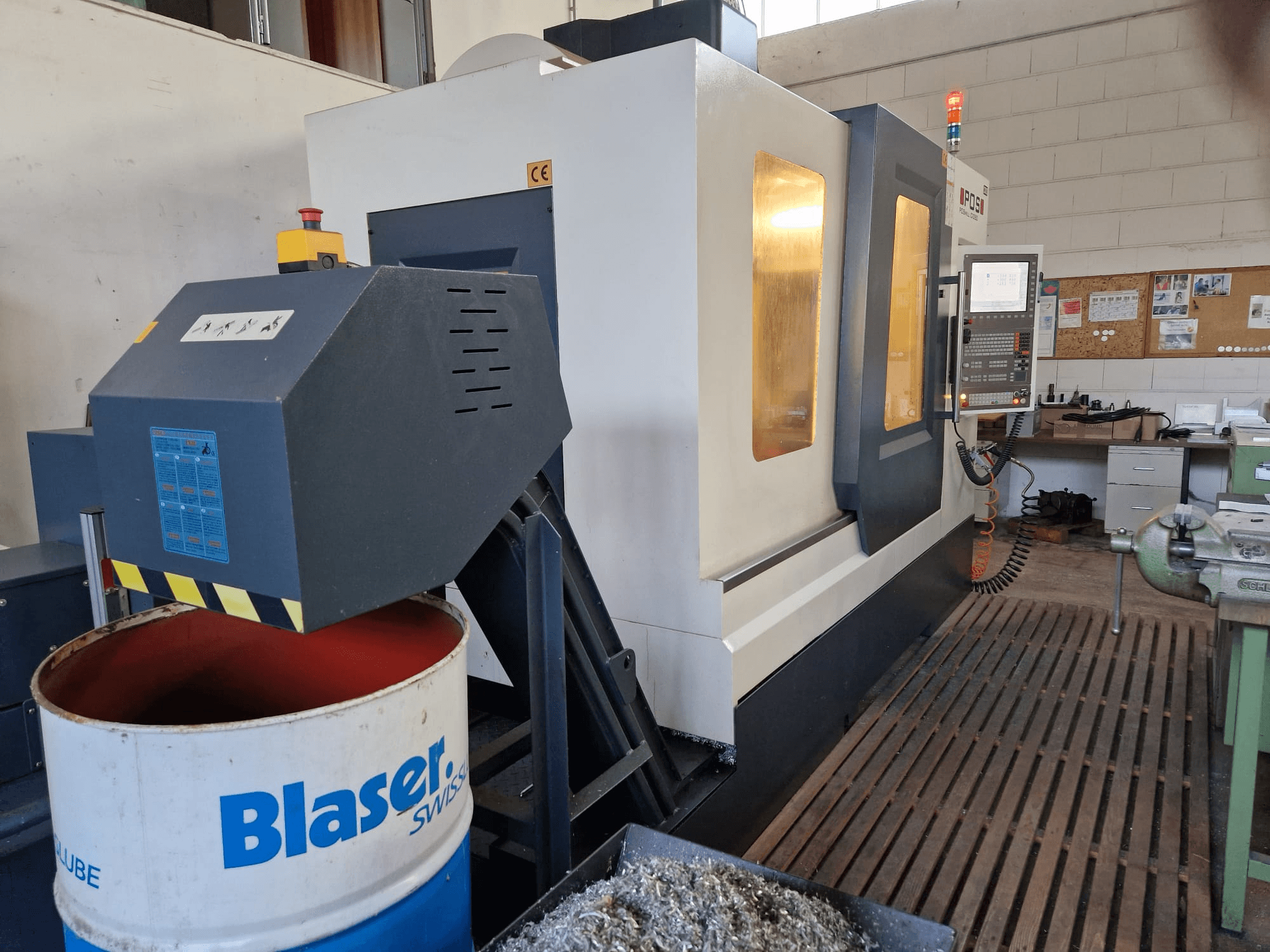 Front view of POSmill C 1050 vertical machining center, with coolant system above Blaser drum and control panel visible.