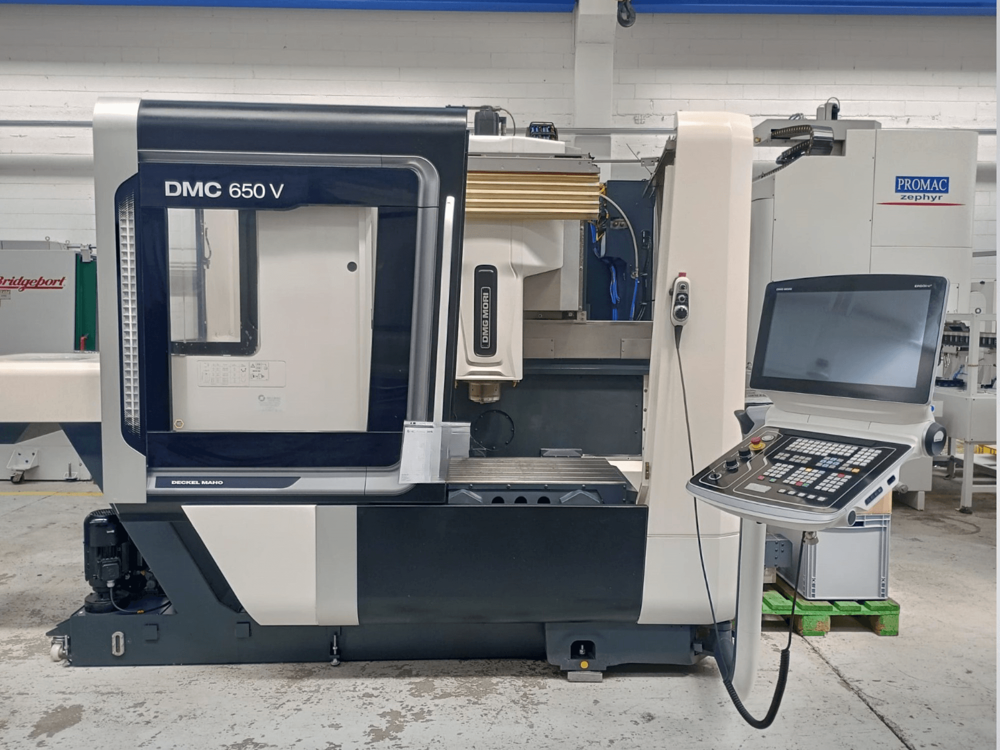 Decker Maho DMC 650 V CNC machine side view, featuring a control panel with buttons and a screen, in industrial setting.