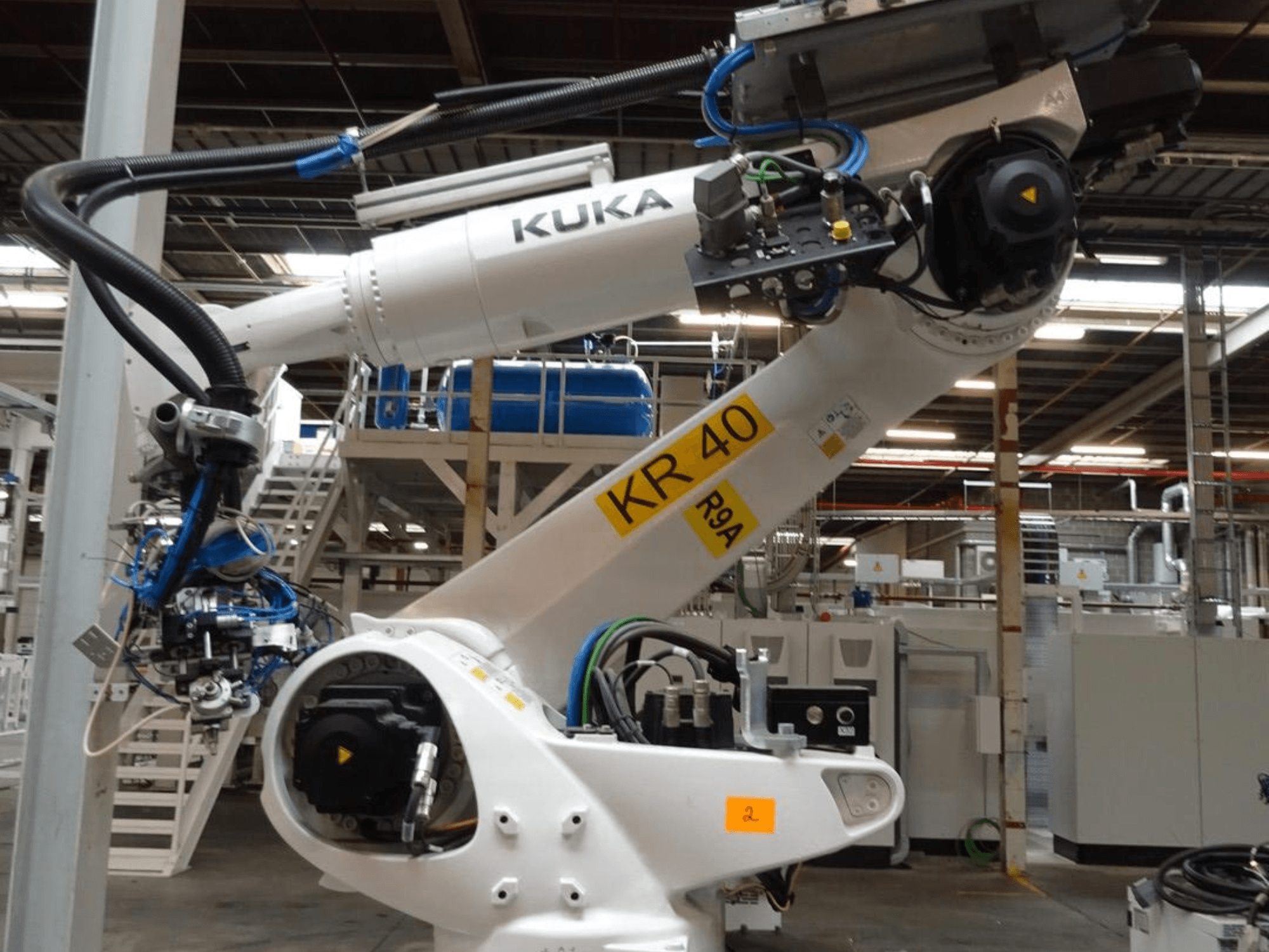 KUKA KR 120 R3100-2 robot arm in side view, showcasing control panel and mechanical components, set in an industrial environment.