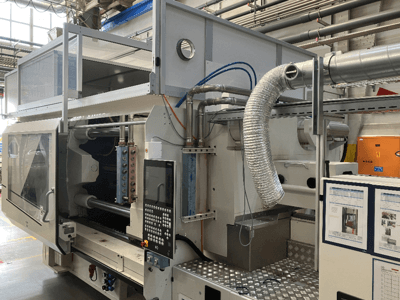 Industrial machine from Brand X, side view showing control panel, ductwork, and machinery components in a factory setting.