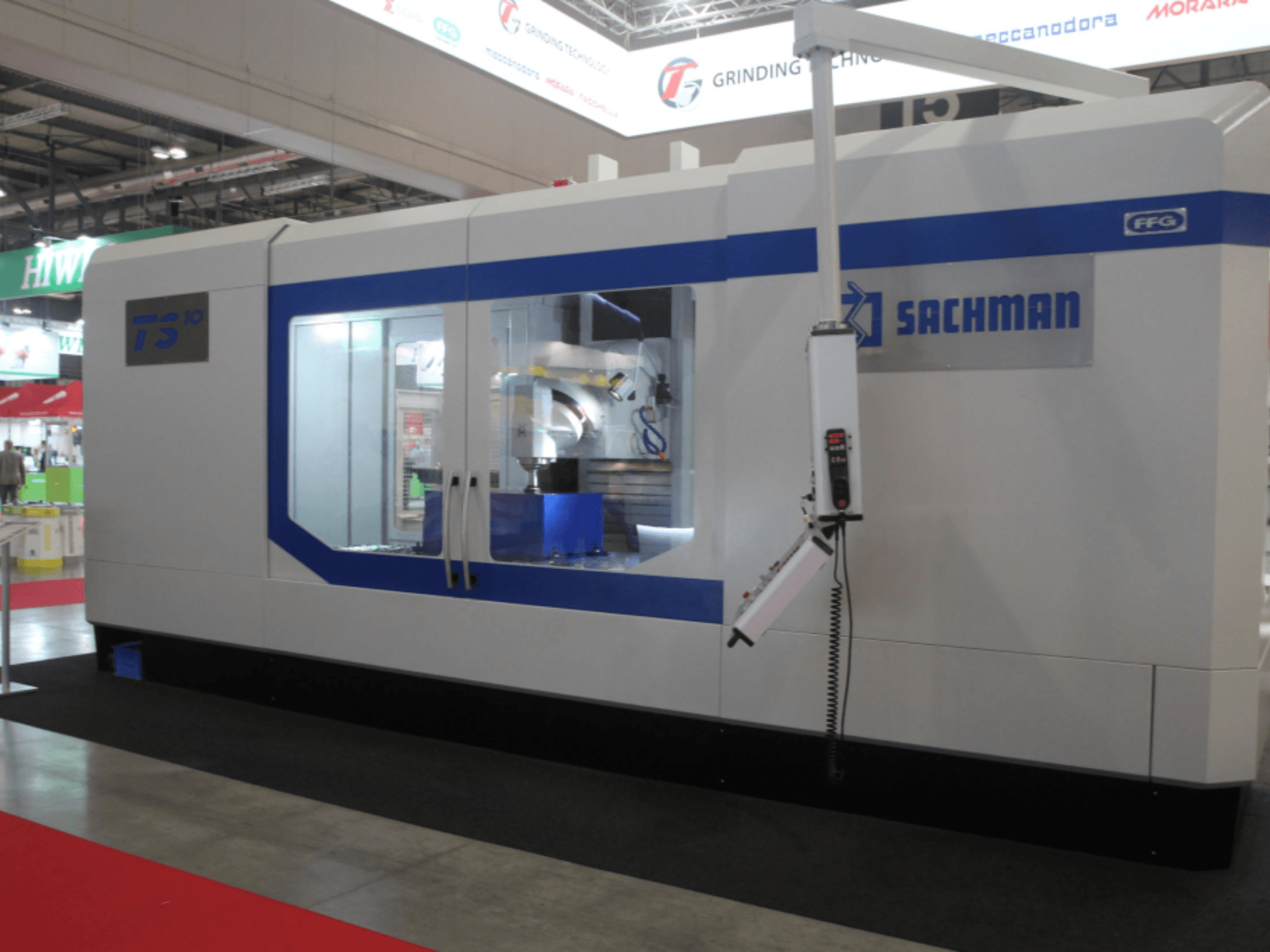 SACHMAN TS10 bed type milling machine, front view, showcasing controls, workspace, and sleek design on a trade show floor.
