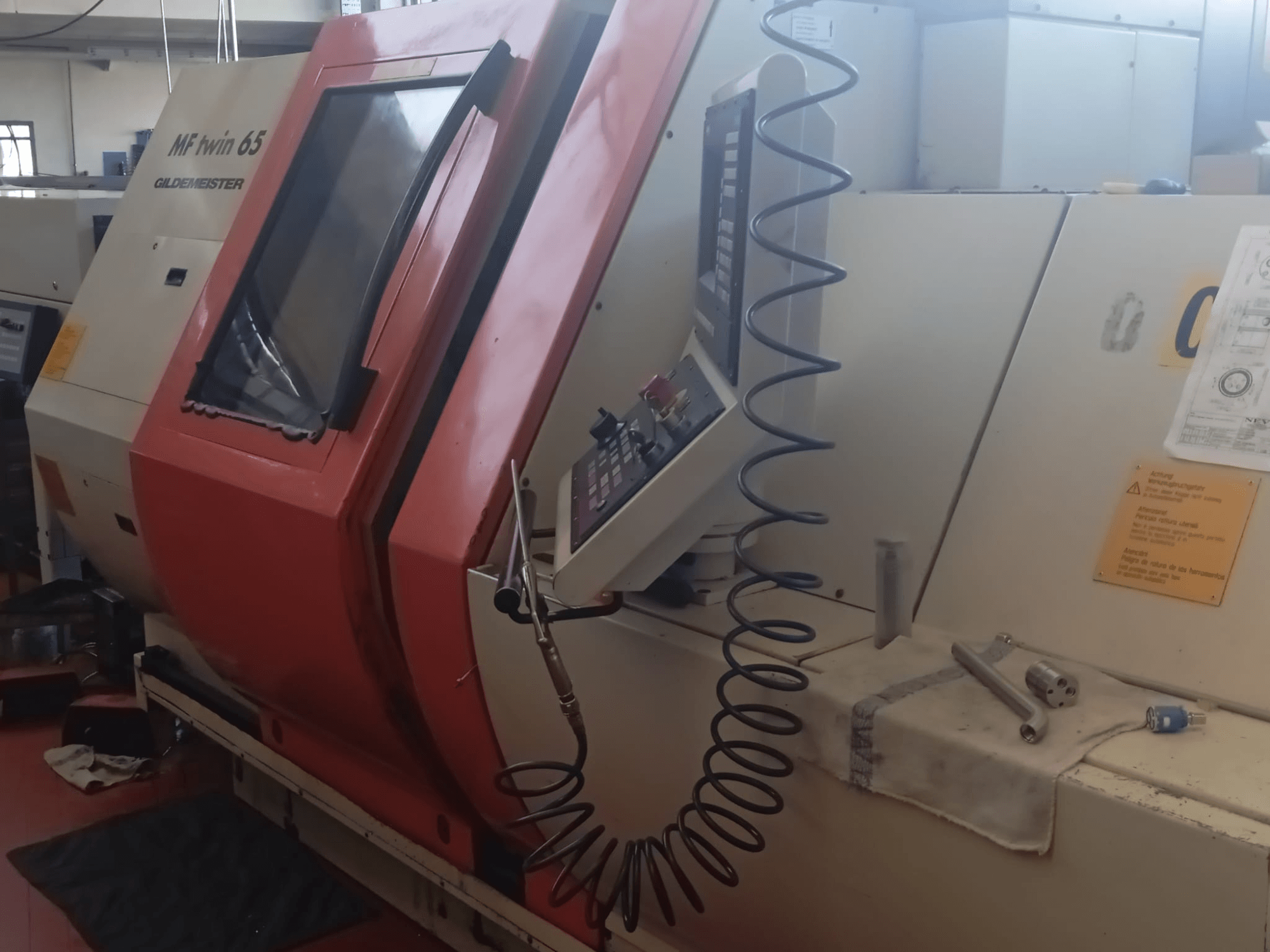 Orange and white MF twin 65 Gliedemeister machine, front view, featuring control panel and tools on a cloth.