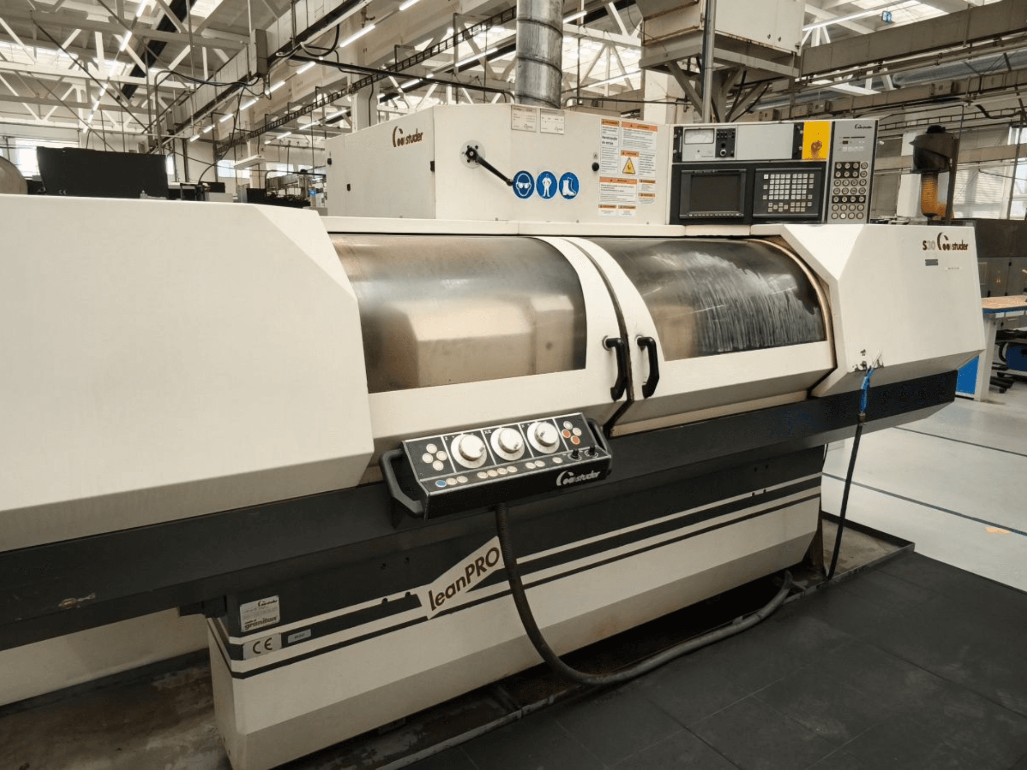 STUDER S30 LEAN PRO cylindrical grinding machine, side view, showcasing control panel and grinding wheel cover in an industrial setting.