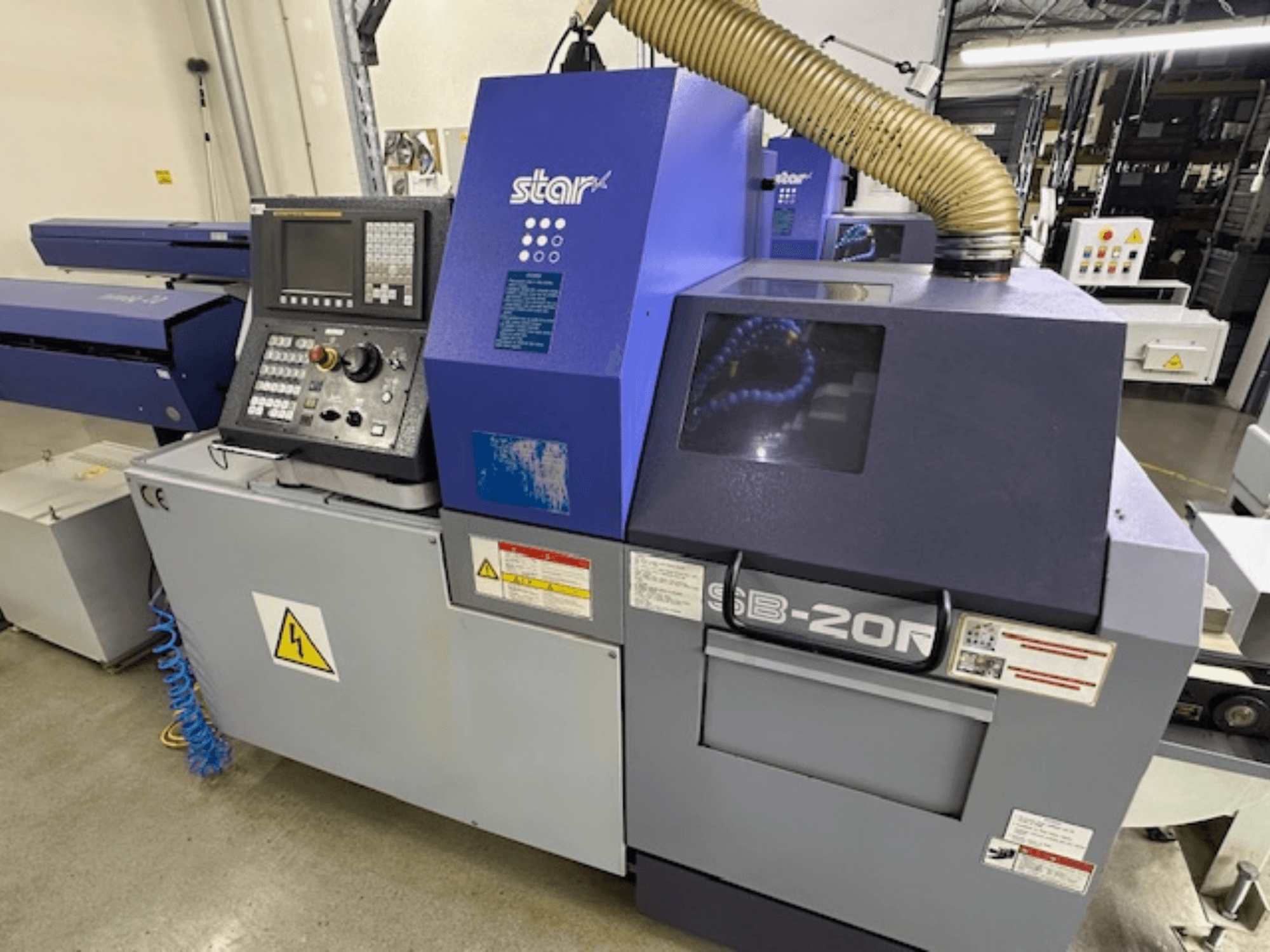 Star SB-20R type N Swiss type turning machine, front view, featuring control panel, suction hose, and visible hazard symbols.