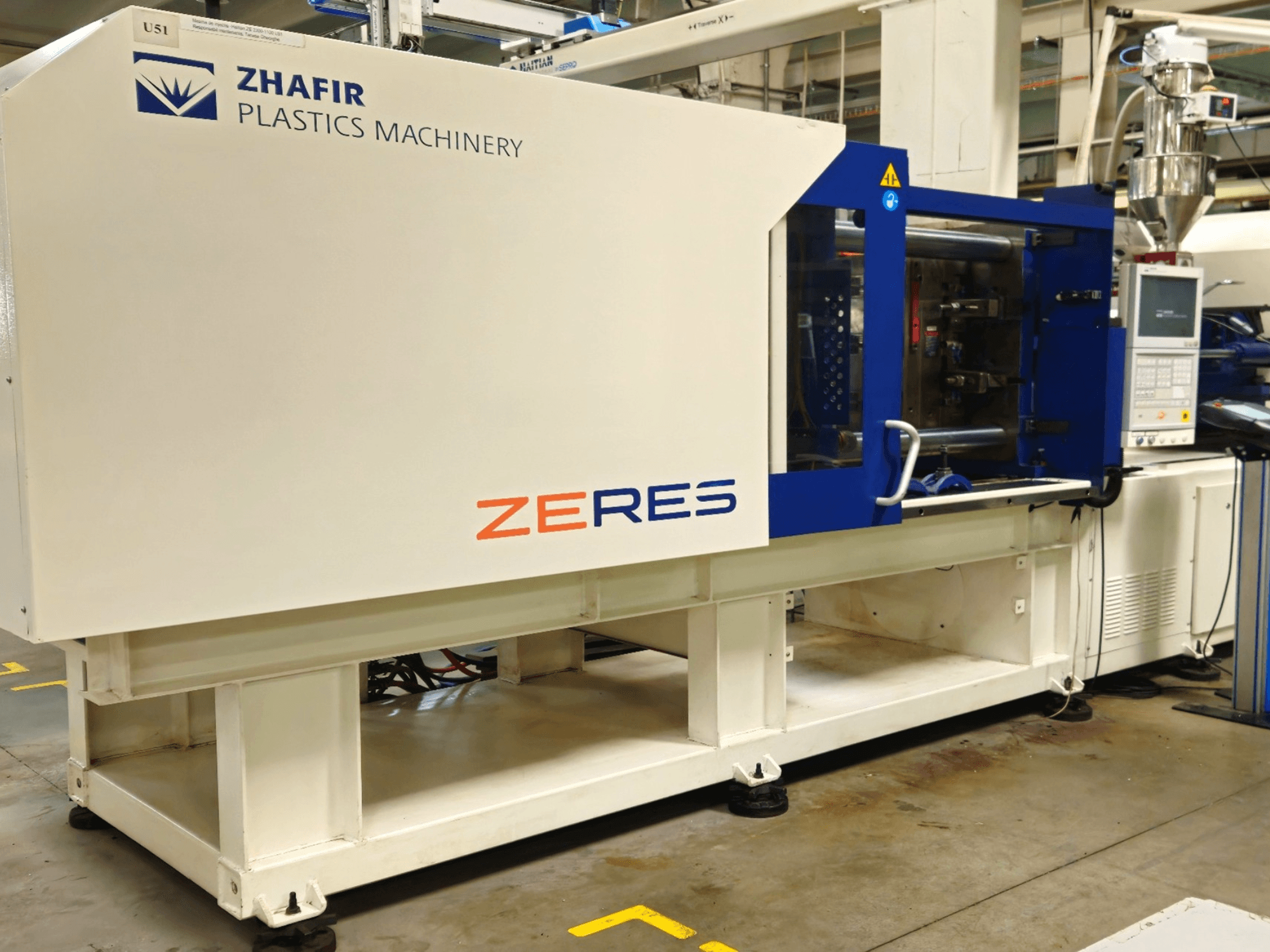 Zhafir Zeres plastic injection molding machine, side view, showing control panel, hopper, and sleek white/blue design.