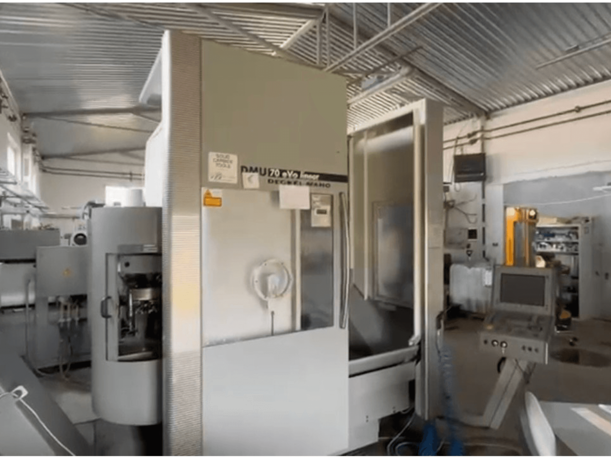 DMU 70 eVo linear CNC machine in a workshop, front view, featuring a control panel and a modern design.