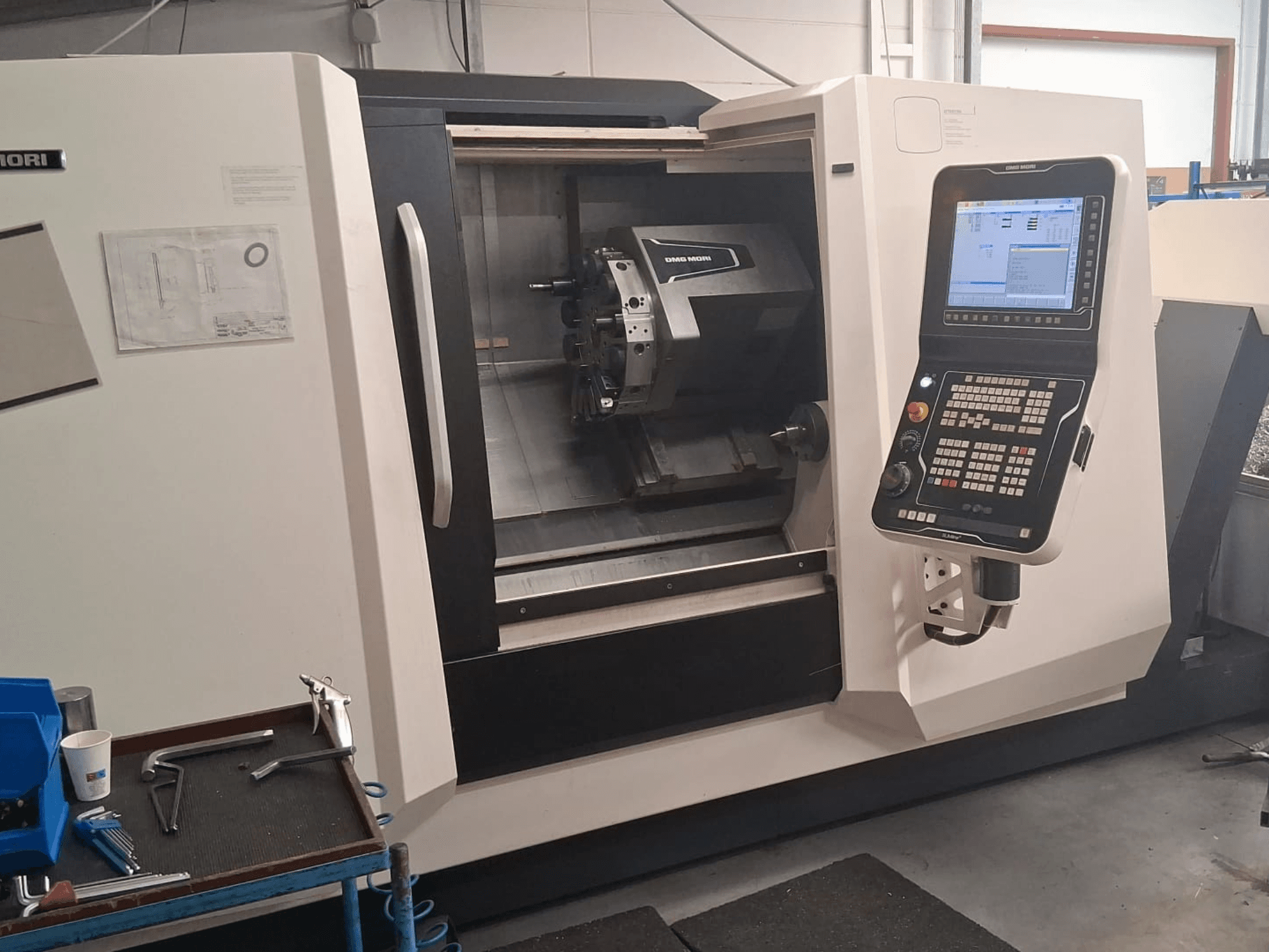 DMG MORI CLX450 horizontal turning machine in front view, showcasing control panel and work area with tools and documentation.
