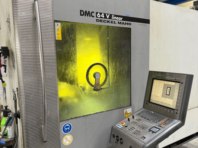 DMC 64 V linear by Deckel Maho, front view of machine with control panel and yellow-tinted window showing inside mechanisms.