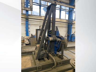 Industrial machine with a blue motor and metallic frame, viewed from the front in a workshop setting.