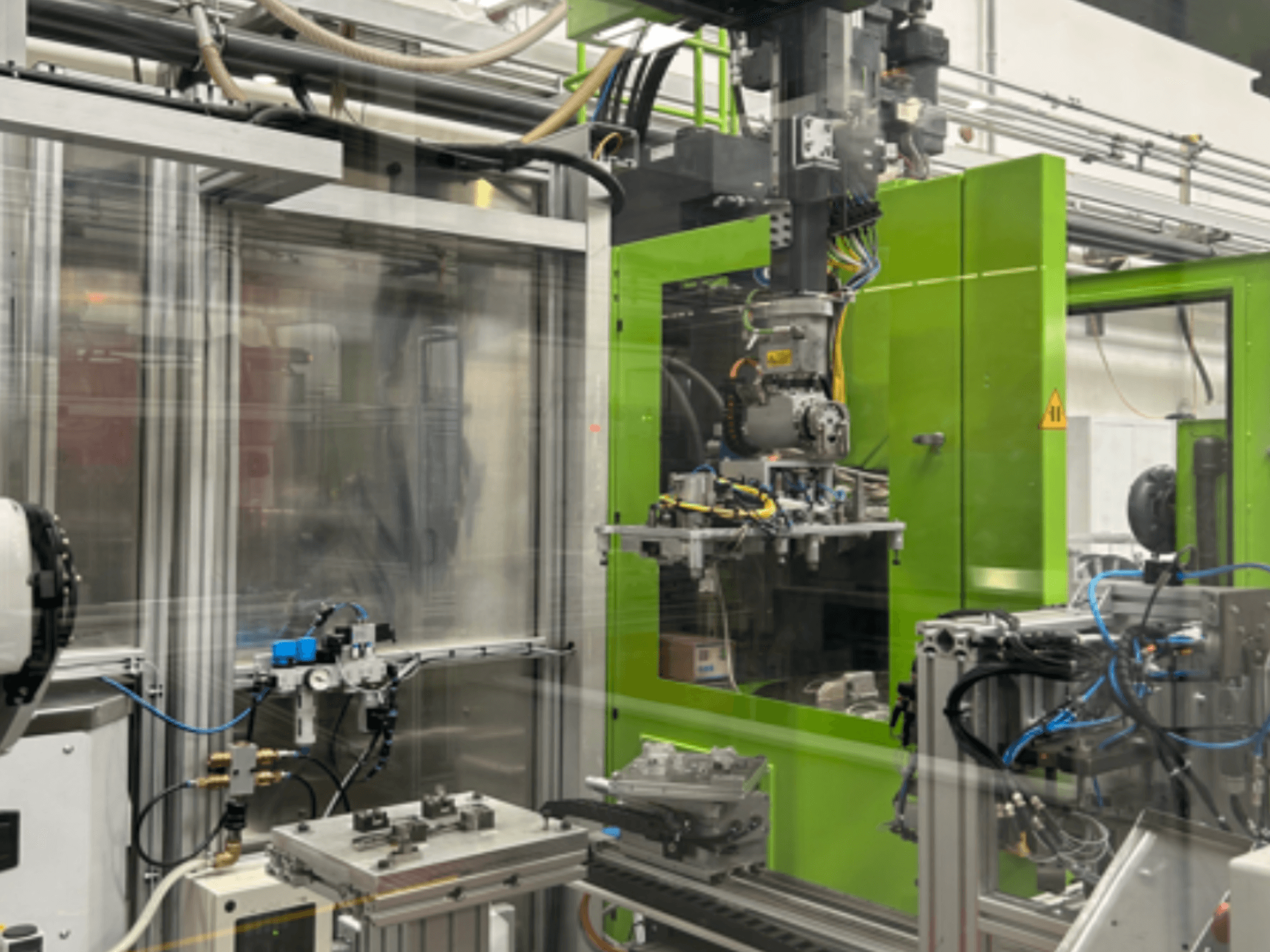 Industrial robotic machinery in green housing, showcasing mechanical components and piping, viewed from the front.