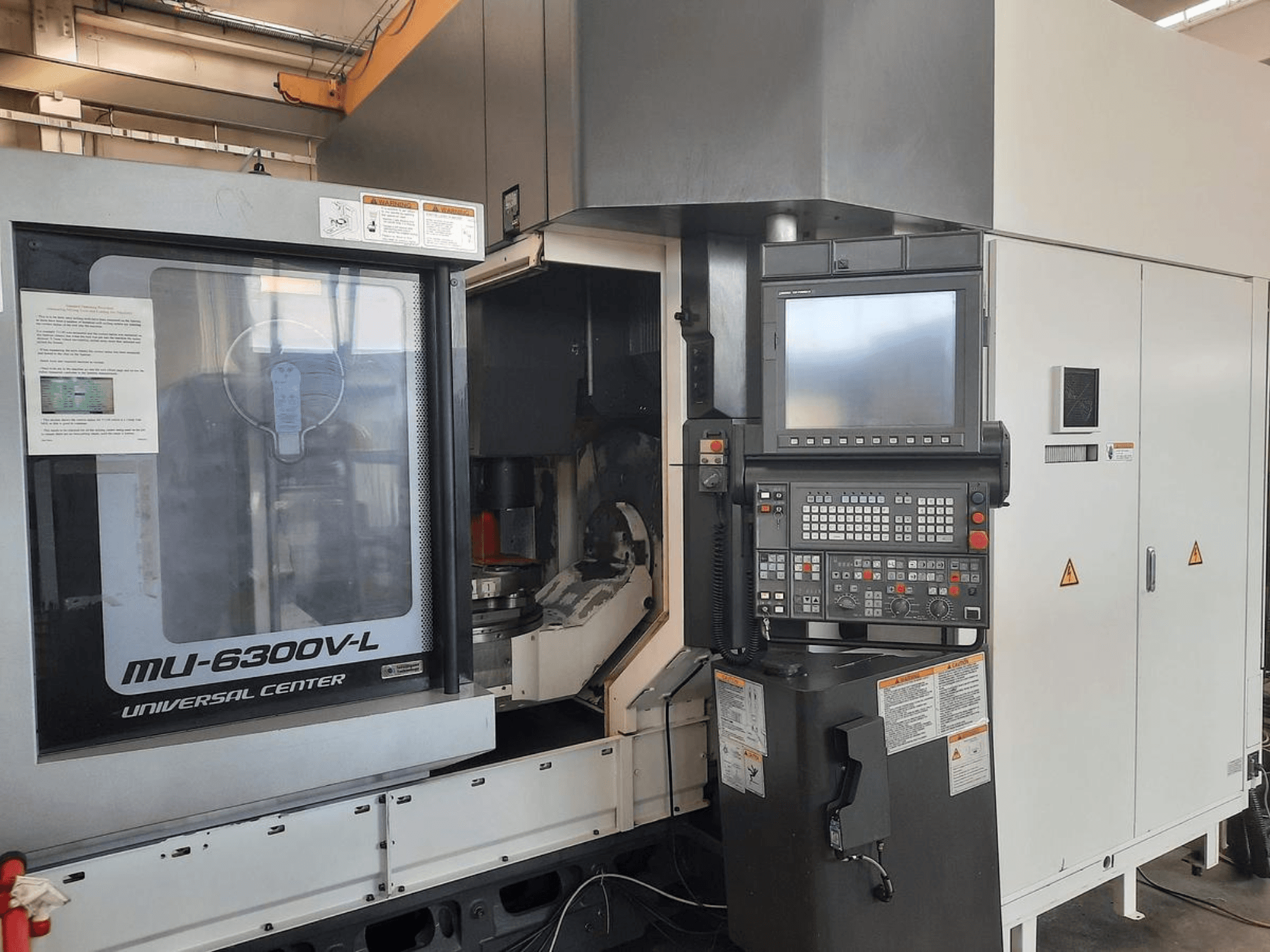 MU-6300V-L Universal Center machine shown from the front, featuring control panel, screen, and operational instructions visible.