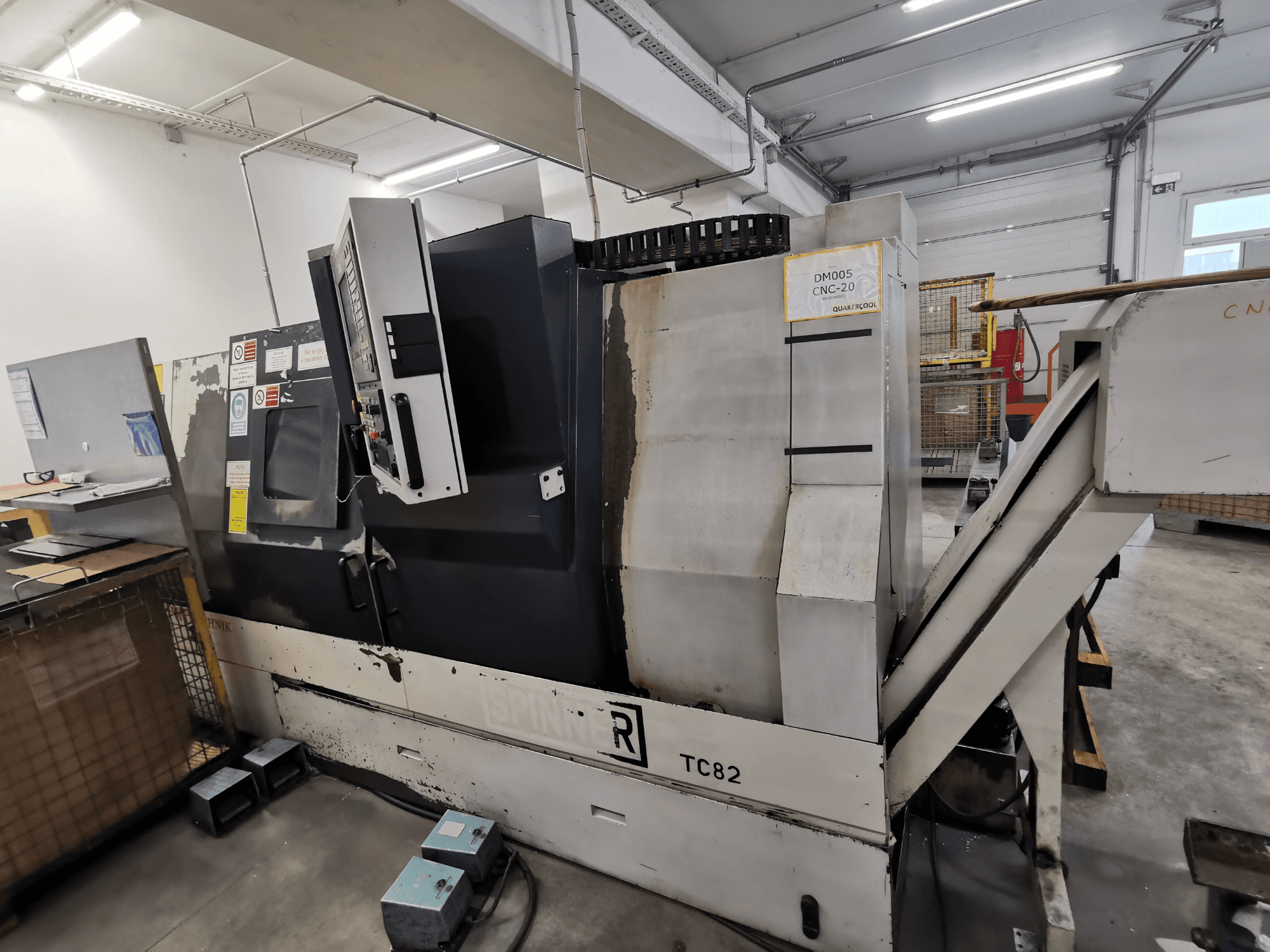 CNC machine, brand Spinner, model TC82, side view showing control panel and scrap removal chute in a workshop setting.