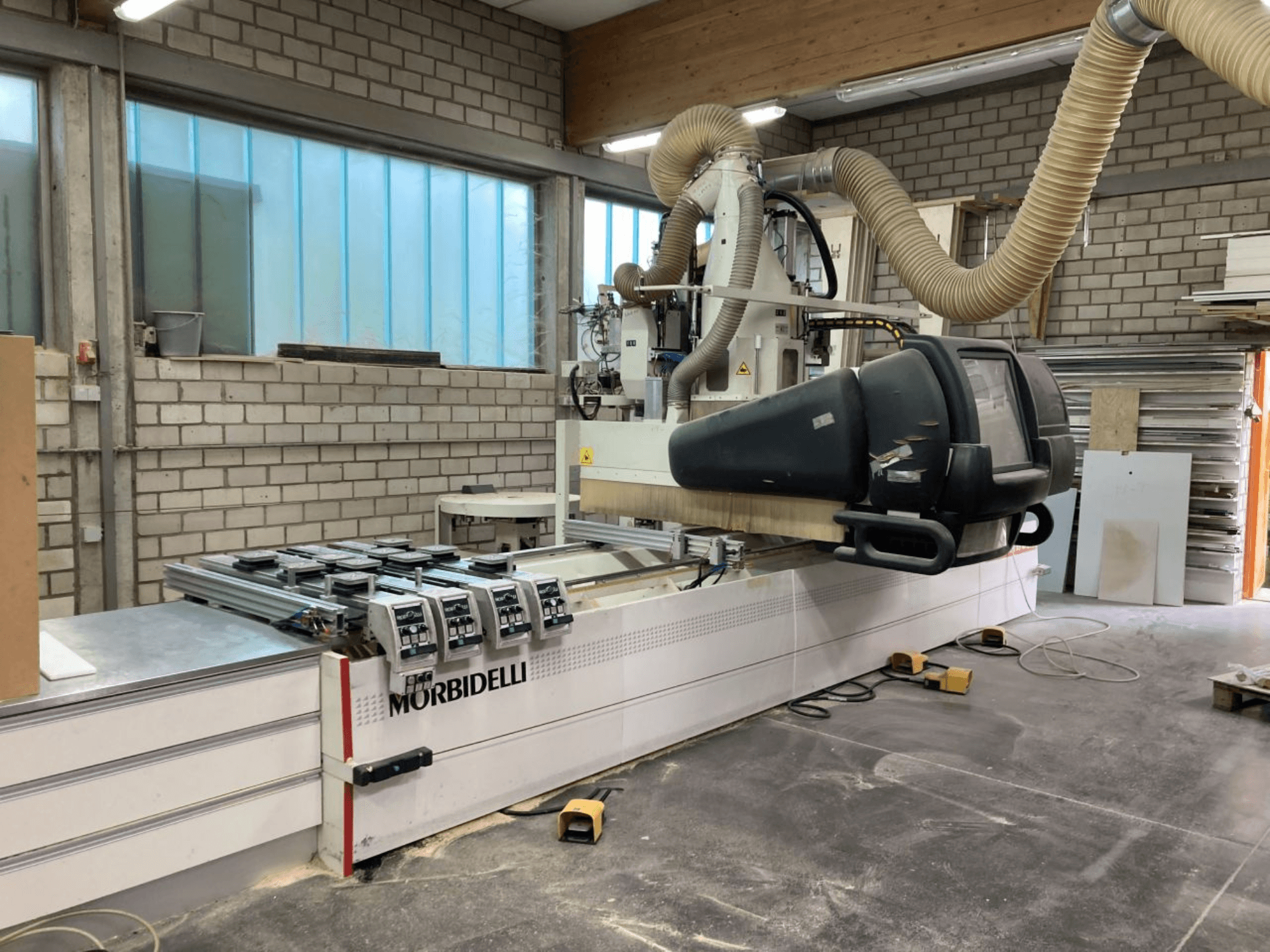MORBIDELLI CNC machine in a workshop, front view with control panel, dust extraction system, and wood piece positioned.