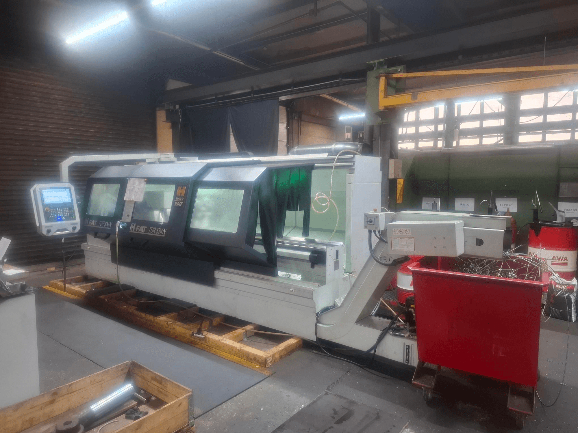Front view of a FAT Tursan CNC machine with control panel, positioned on wooden pallets in a workshop.