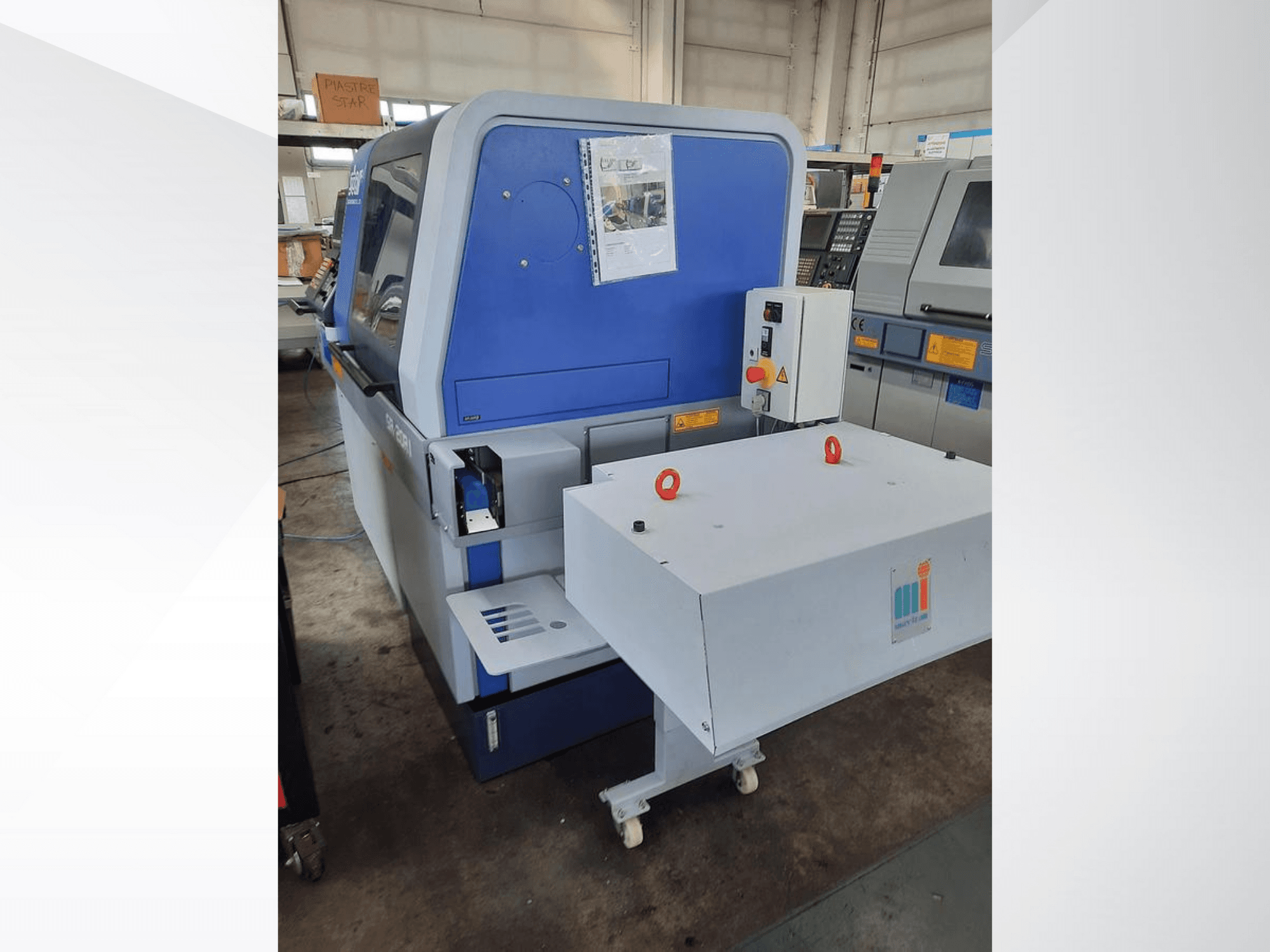 Blue industrial machine with a white conveyor, showing control panel and attached safety features, side view.