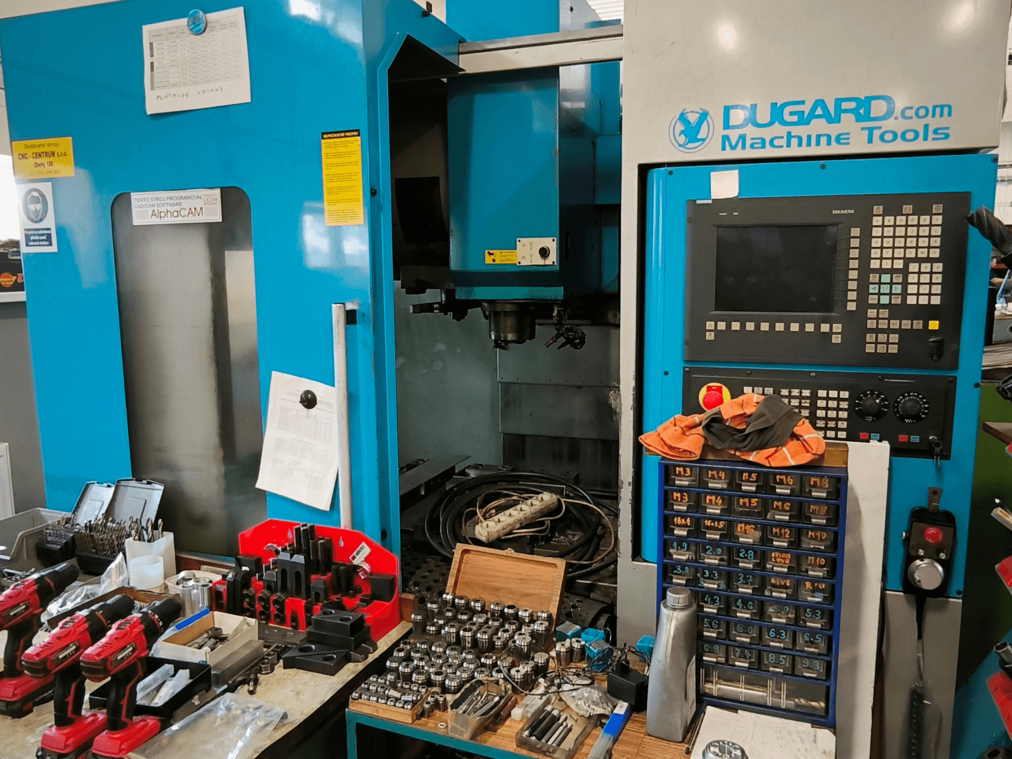Front view of Dugard 850VMC vertical machining centre, displaying control panel, tools, and accessories on a workbench.
