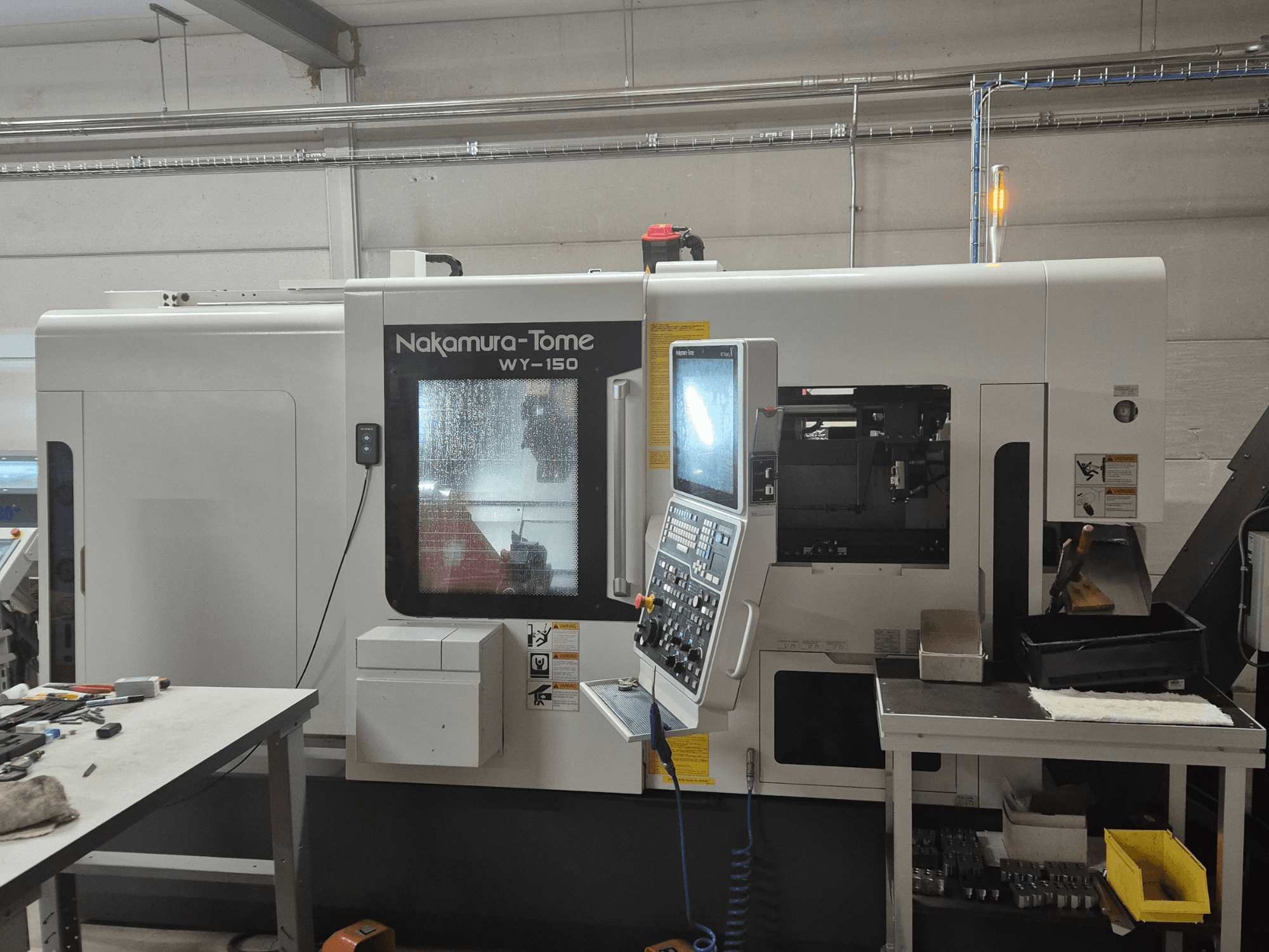 Nakamura-Tome WY-150 CNC lathe in side view, featuring control panel, transparent window, and visible work area.