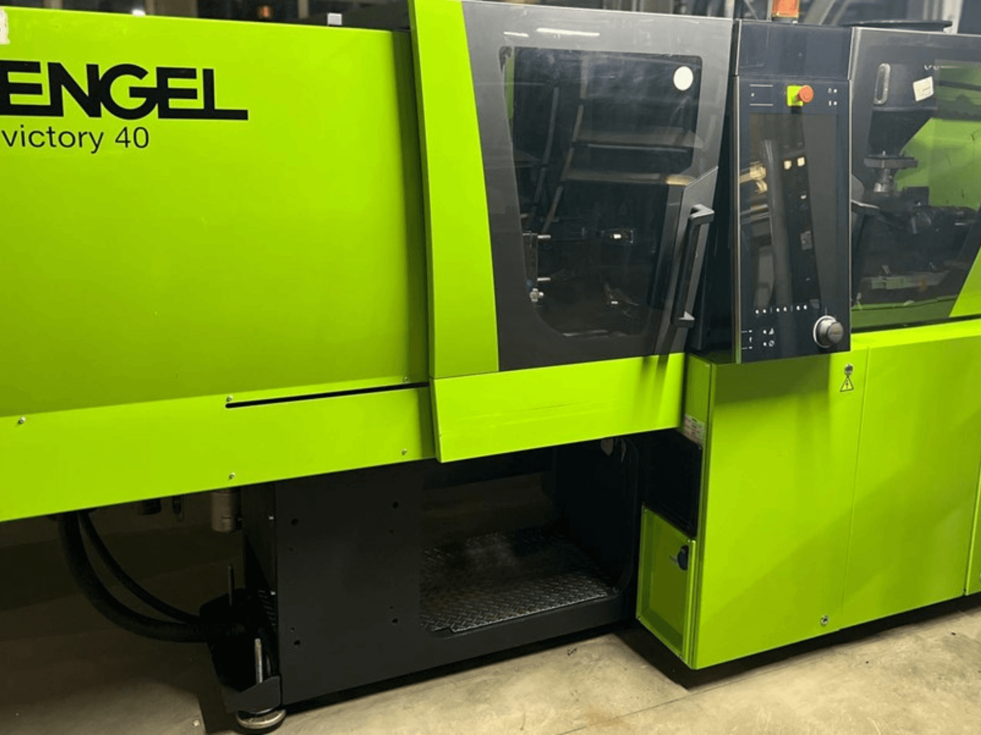 ENGEL Victory 40 injection molding machine in bright green, front view showing control panel and access door with warning label.