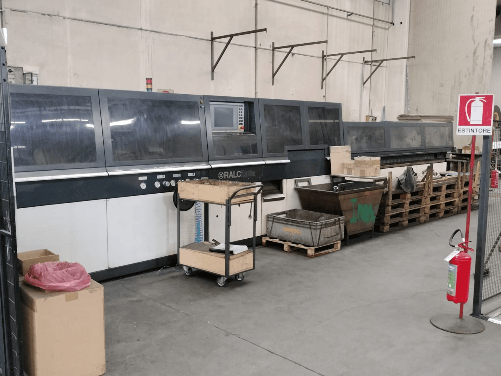 RALC industrial machine in a factory setting, front view, with control panel visible; wooden pallets and fire extinguisher nearby.