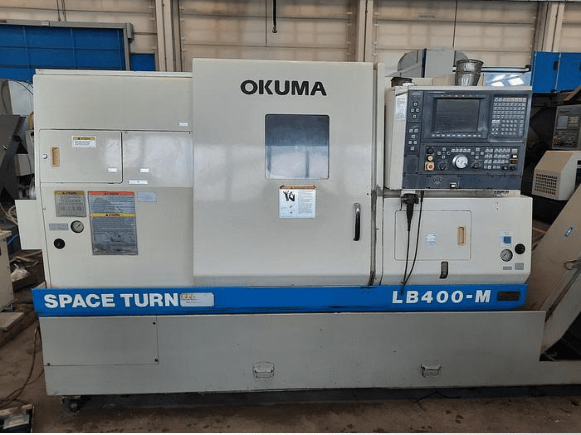 Okuma LB400-M CNC lathe machine, front view with control panel, warning labels, and blue "SPACE TURN" branding visible.