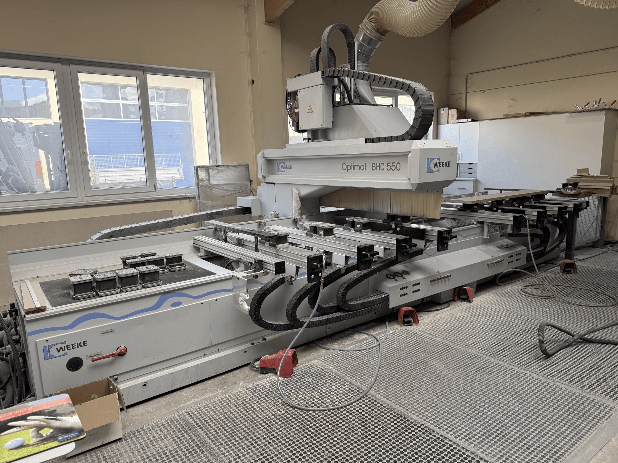 CNC Wood Machining Centre Weeke Optimat BHC 550, front view showing tool head and worktable, with dust extraction system visible.