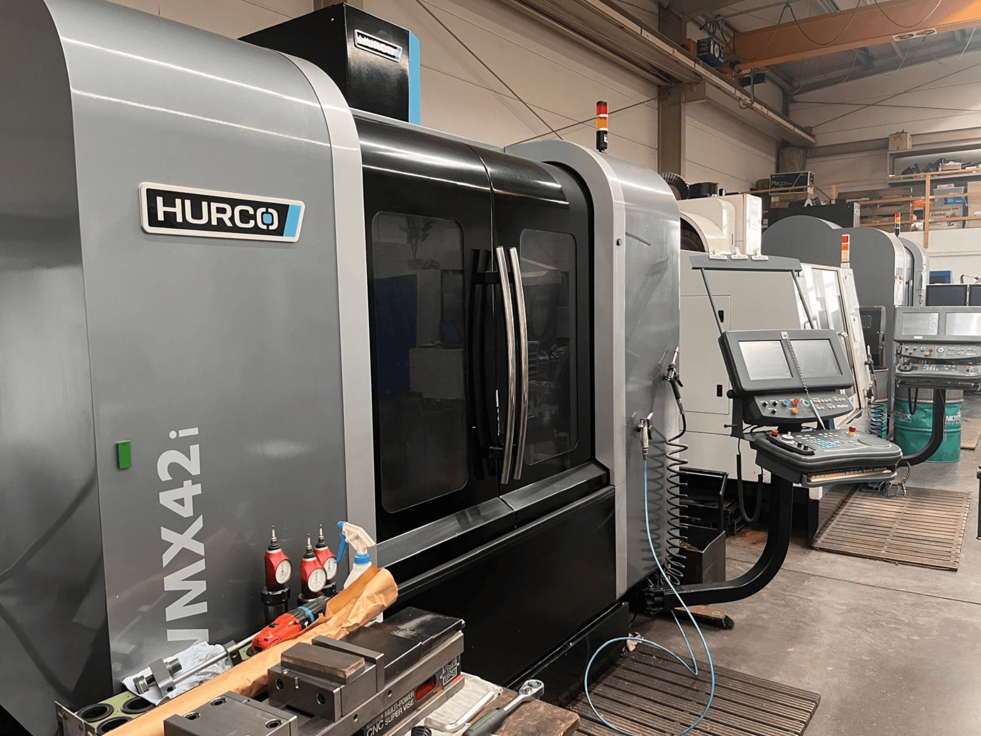 Hurco VMX42i CNC machine in a workshop, front view, featuring control panel and various tools on the workbench.
