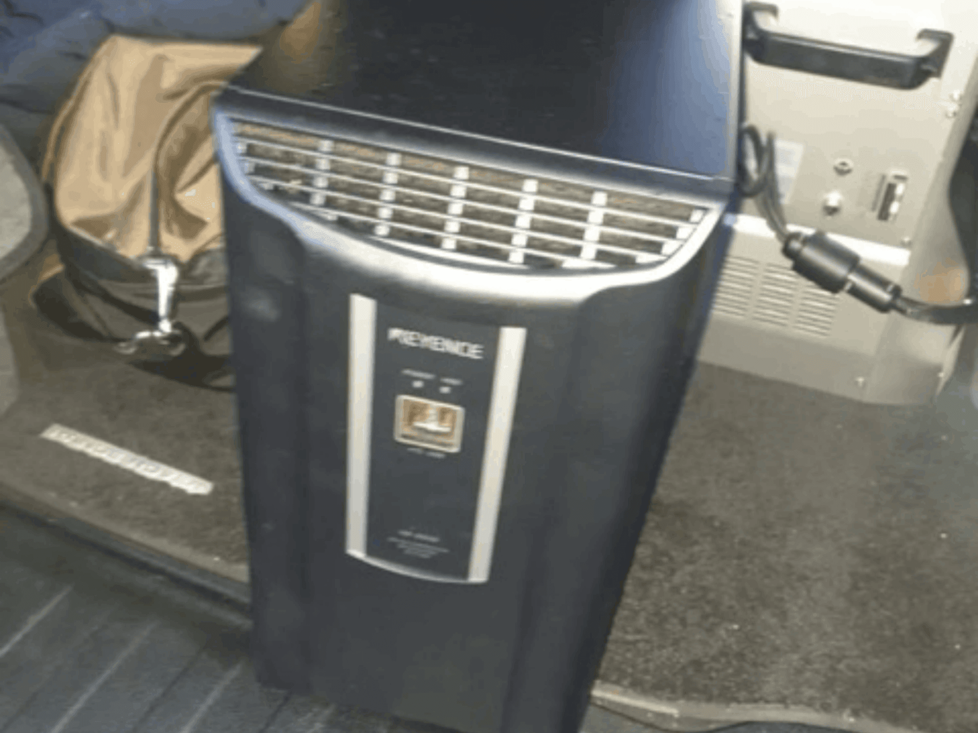 KEYENCE IM-8030 automation system in a front view, showcasing control panel and vents, set against a vehicle interior backdrop.