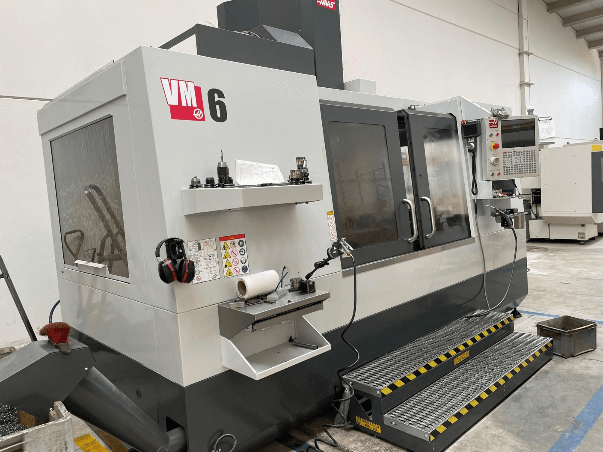 Haas VM-6 vertical machining center, front view showing control panel, tool holders, and safety features.