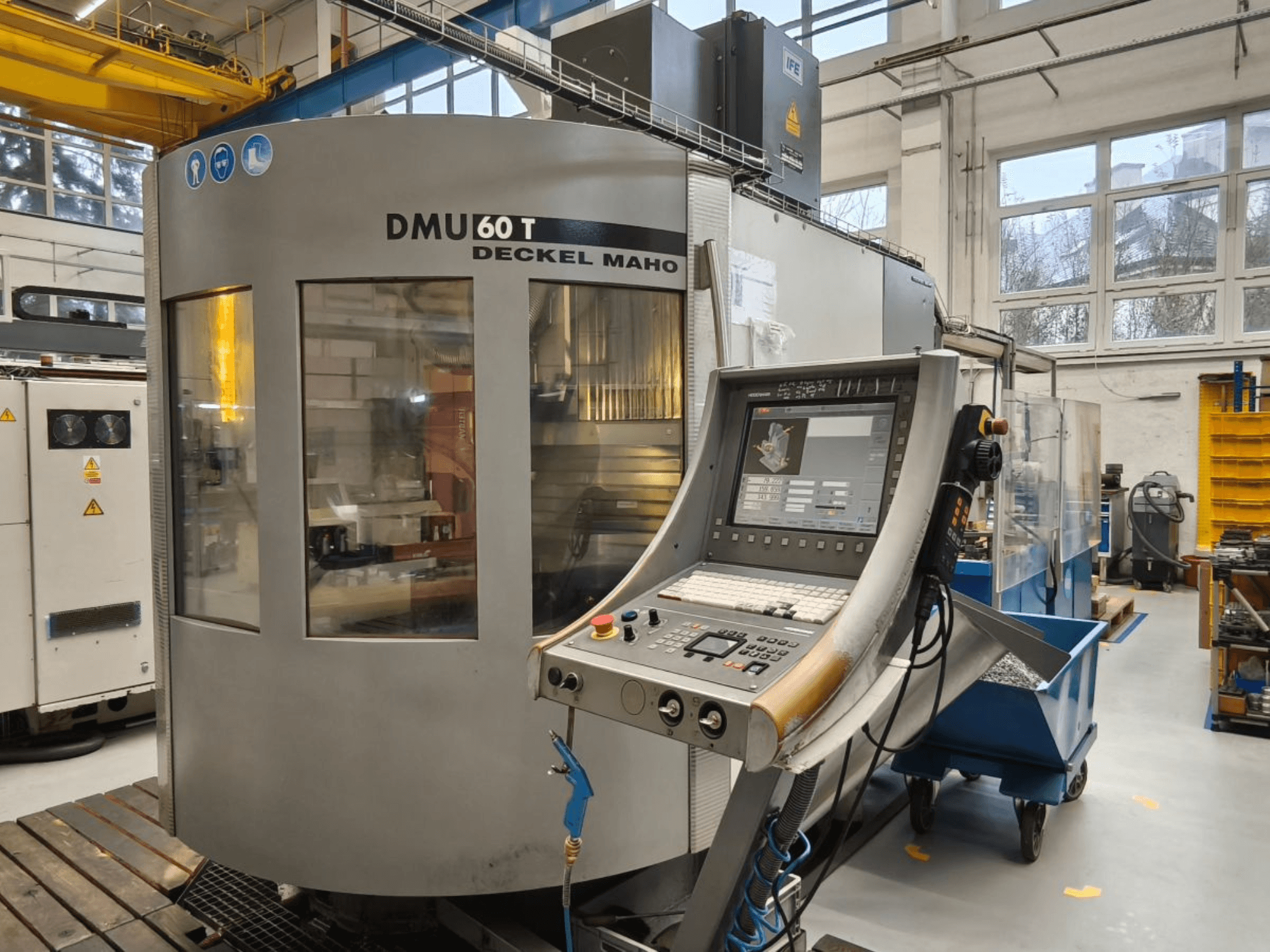 Vertical view of DECKEL MAHO DMU 60T machining center with control panel, displaying precision tools within a workshop.
