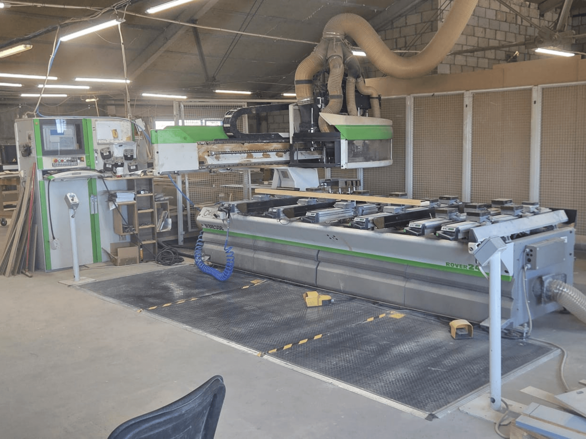 CNC Processing Center BIESSE Rover 24S in a workshop, featuring a control panel and large work surface with wood pieces.