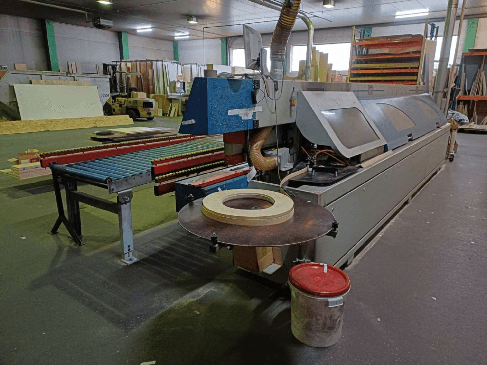 OTT TWISTER edgebander in a workshop, featuring a roller conveyor and circular saw, viewed from the side.