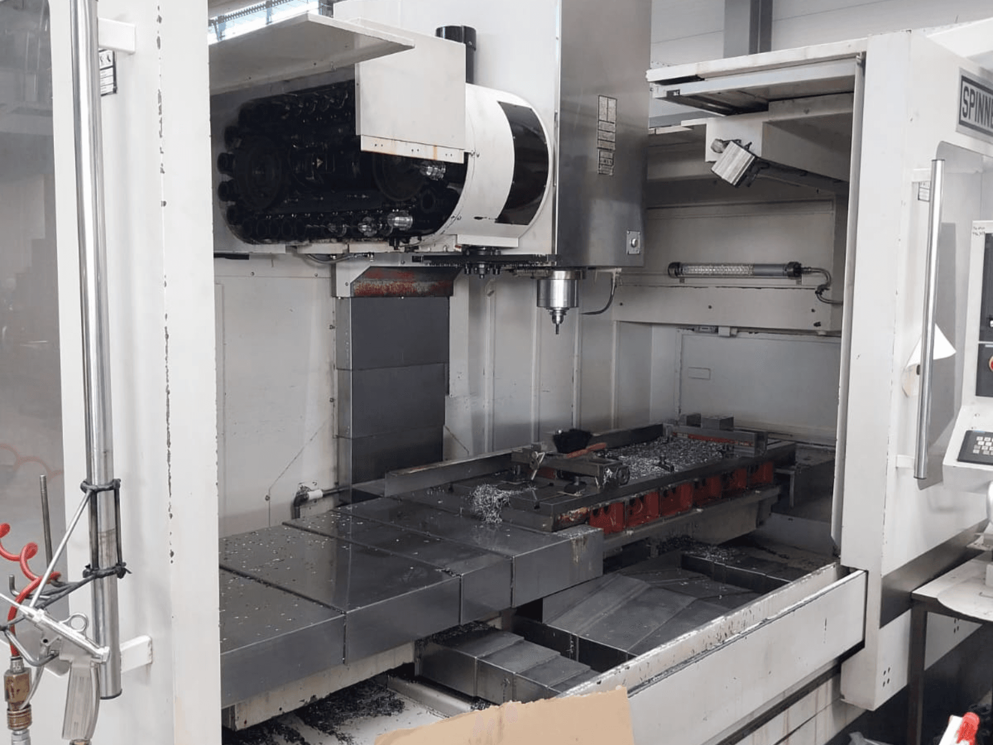 Front view of SPINNER MVC 1600 vertical machining centre showcasing the open workspace, spindle, and metal chips on the table.