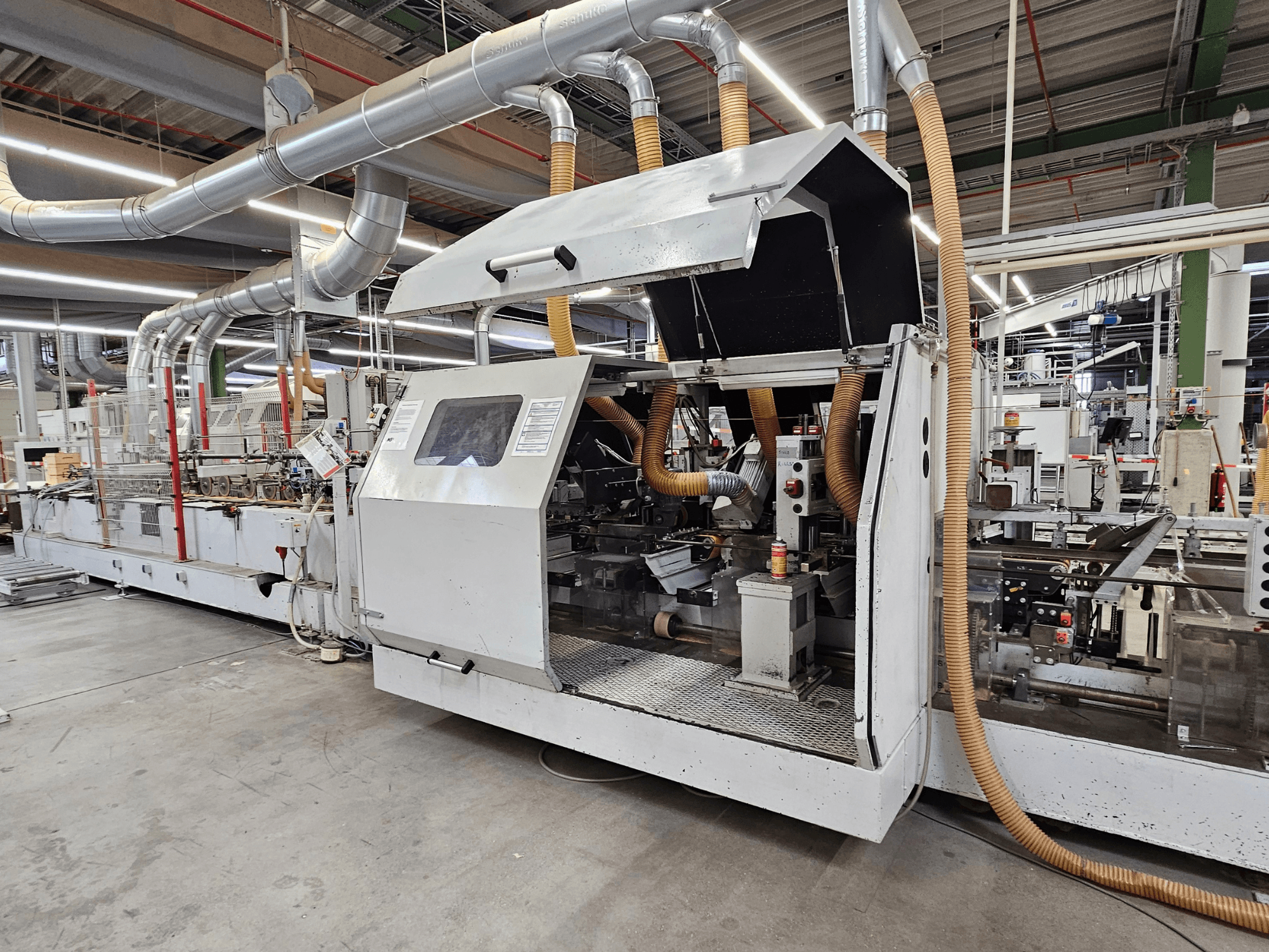 HOMAG FG63 edgebander in a factory setting, side view showing operational components and dust extraction system.