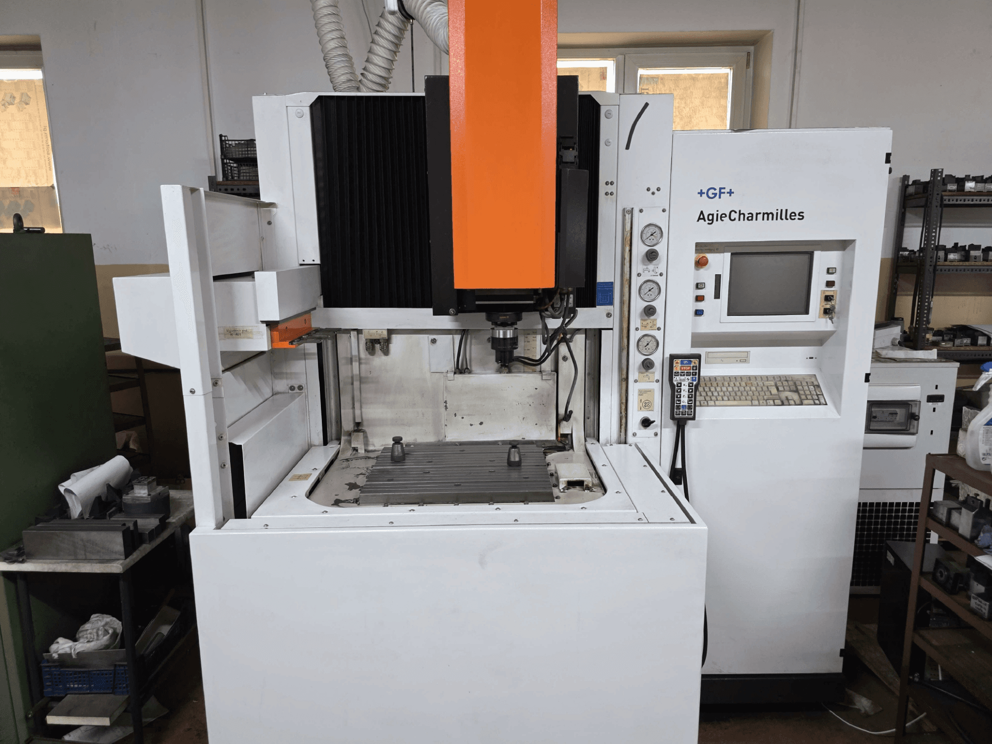 GF AgieCharmilles CNC machine, front view with a prominent orange spindle, digital control panel, and mounted drill table.