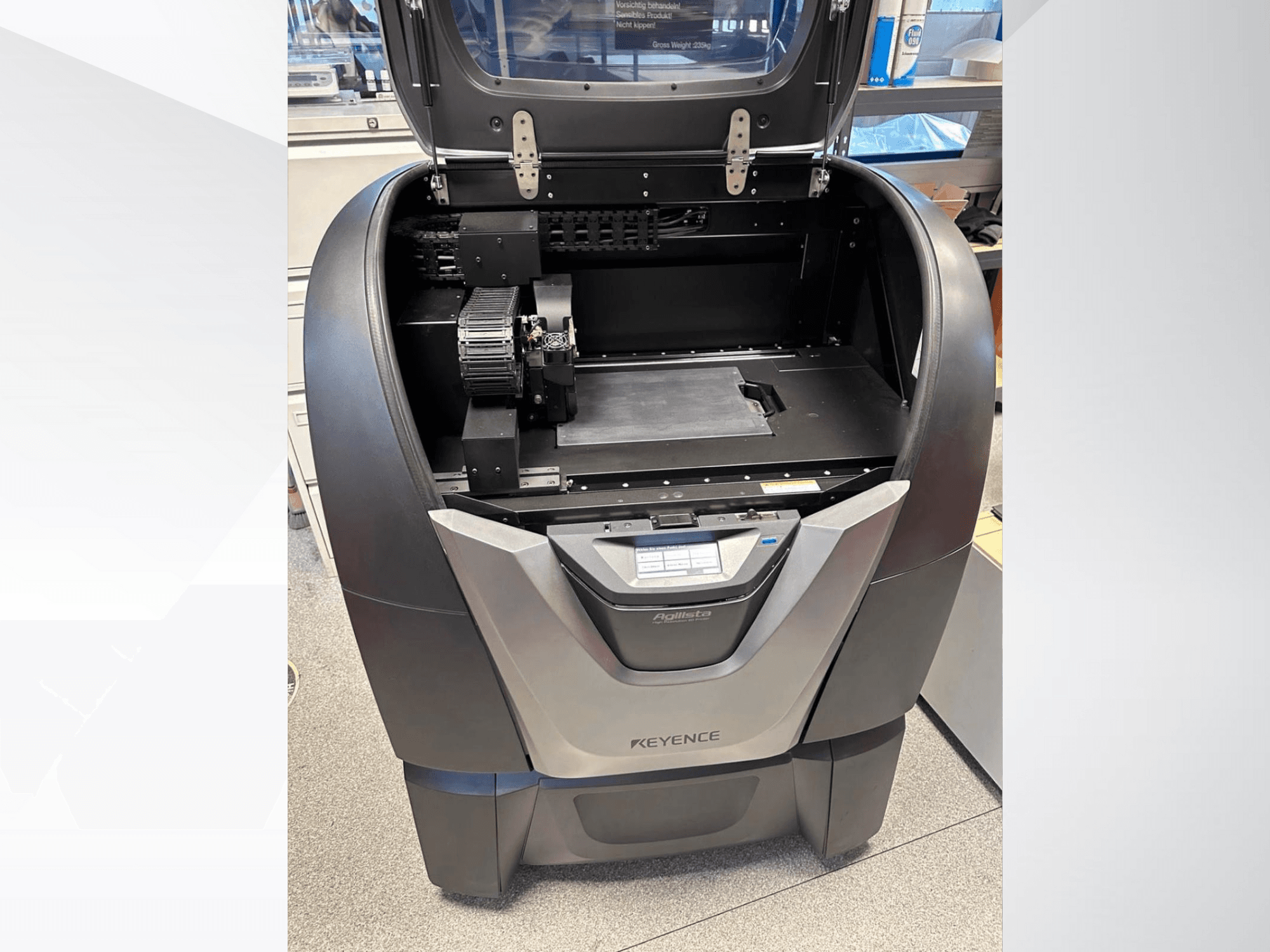 KEYENCE Agilista 3D printer, front view, reveals open top, large build platform, and internal mechanical components.