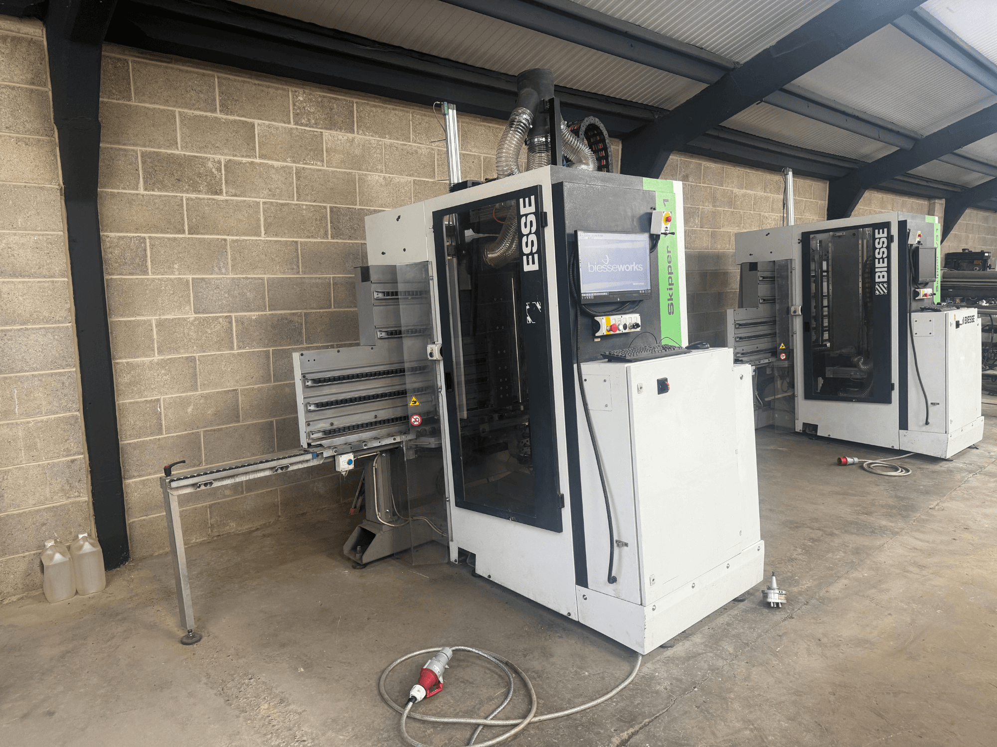 BIESSE Skipper v31 wood boring machine in side view, featuring control panel and adjacent machinery, set in a workshop.