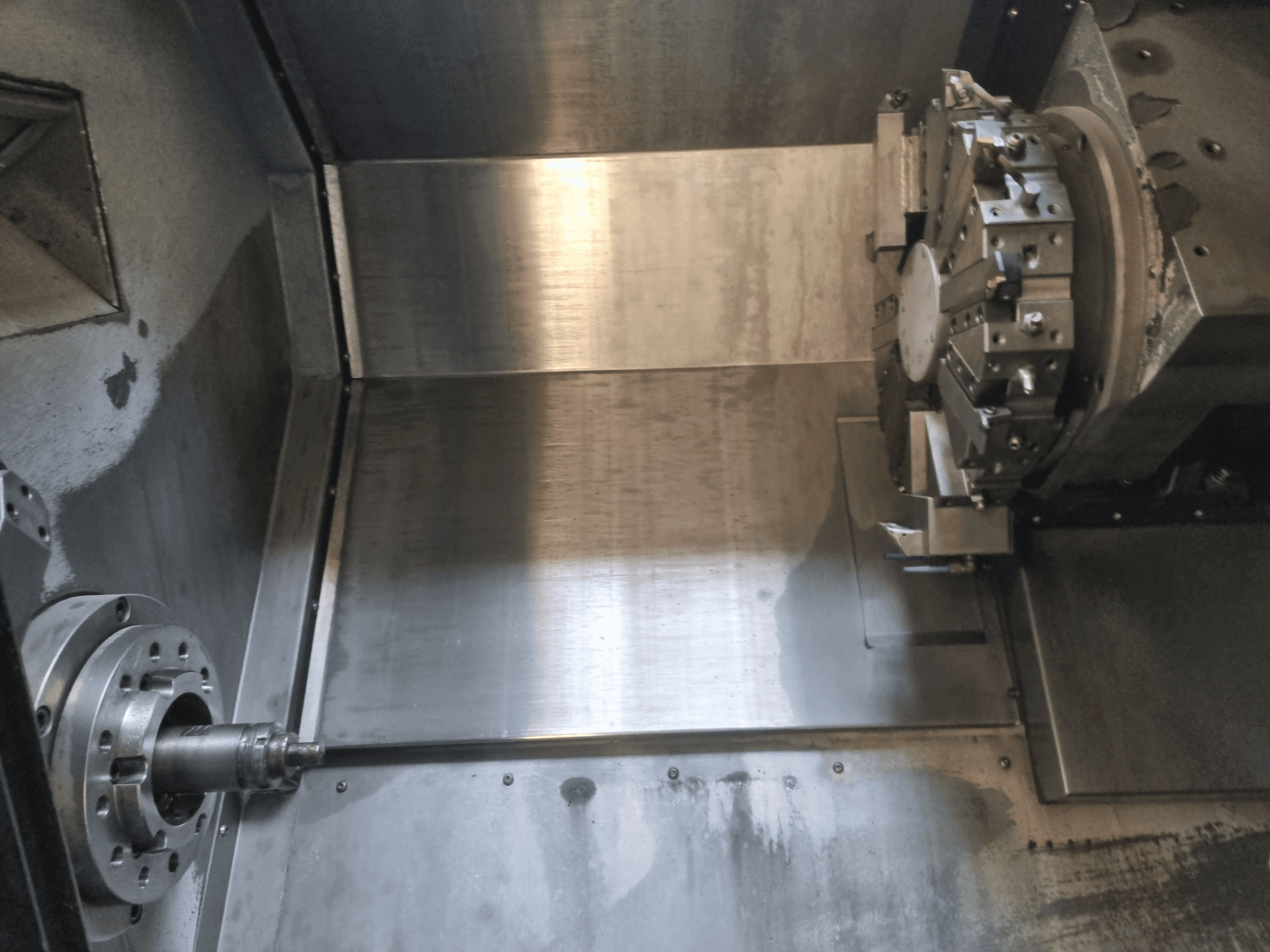 Interior view of a CNC lathe, featuring a rotating spindle and metal work surface, showcasing industrial precision engineering.