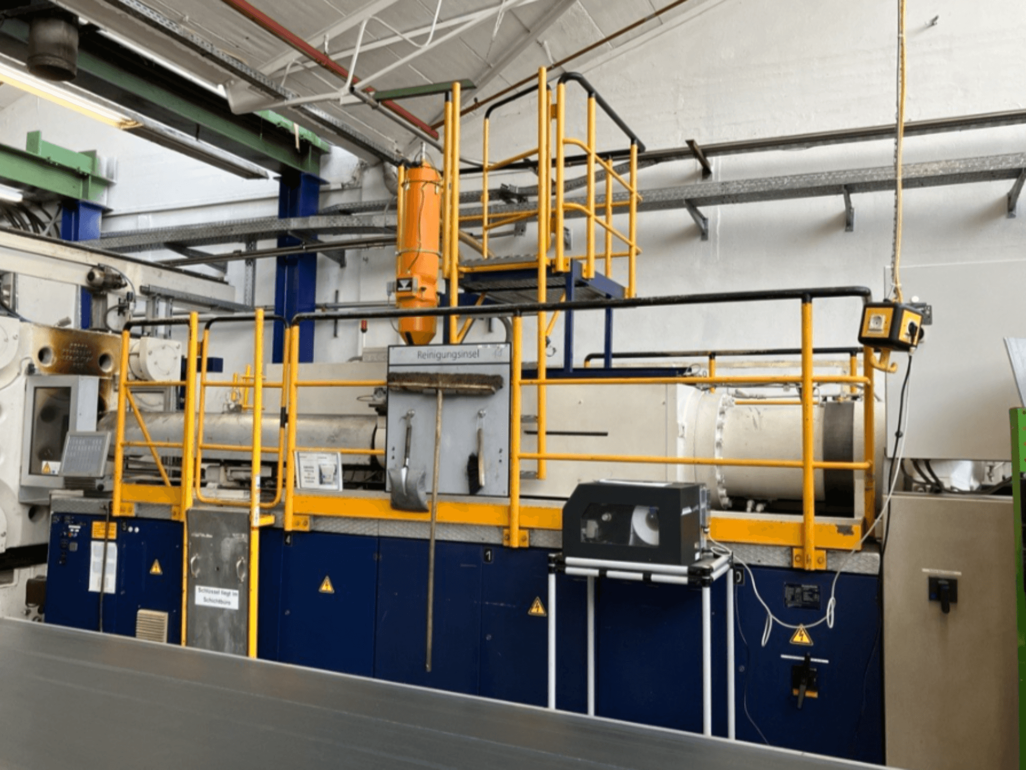 Krauss Maffei 1000-8000 M hydraulic injection molding machine, side view with safety railing and control panel visible.