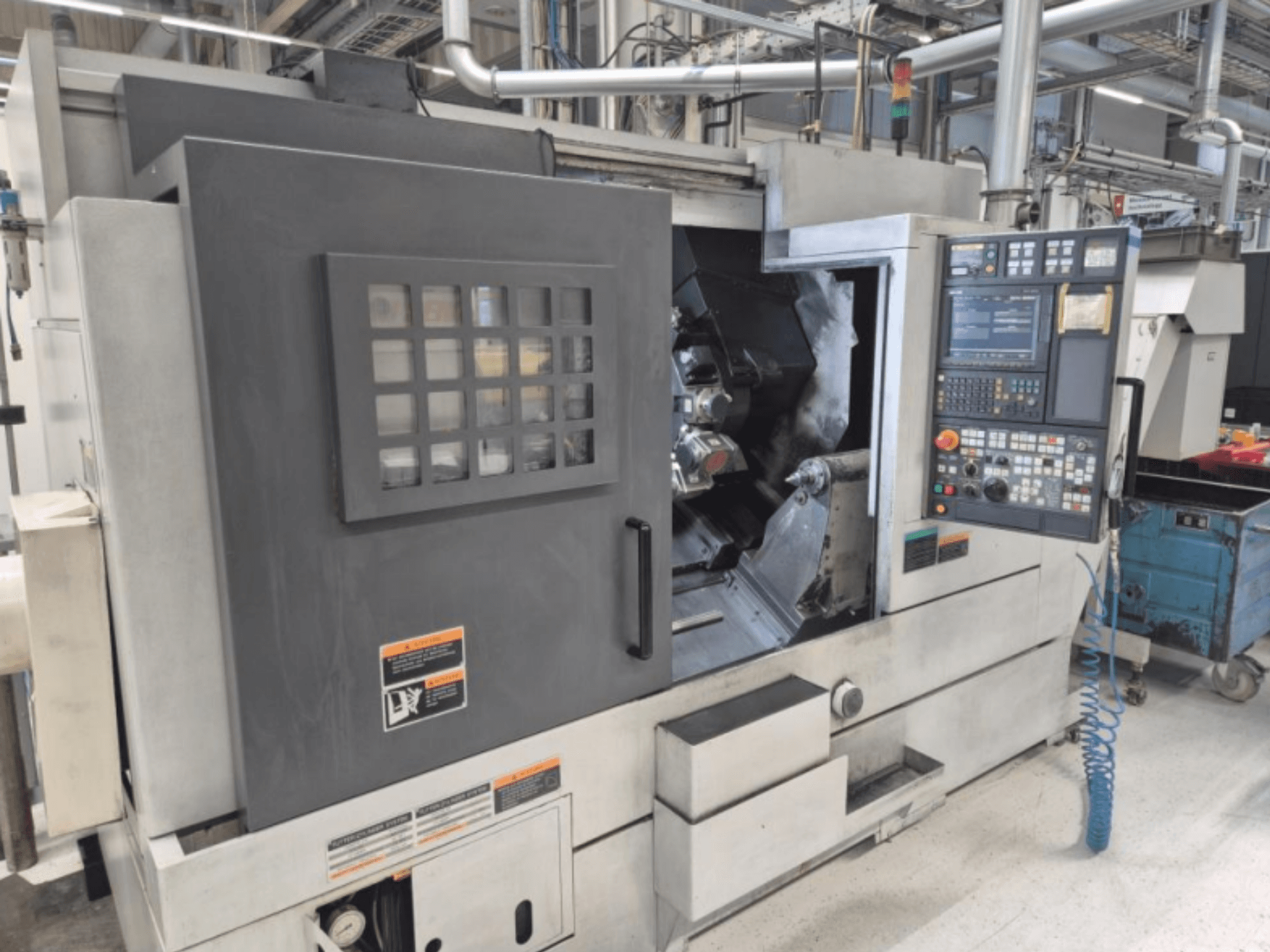 CNC lathe machine with control panel, front view. Features a visible work area and safety window, brand unknown.