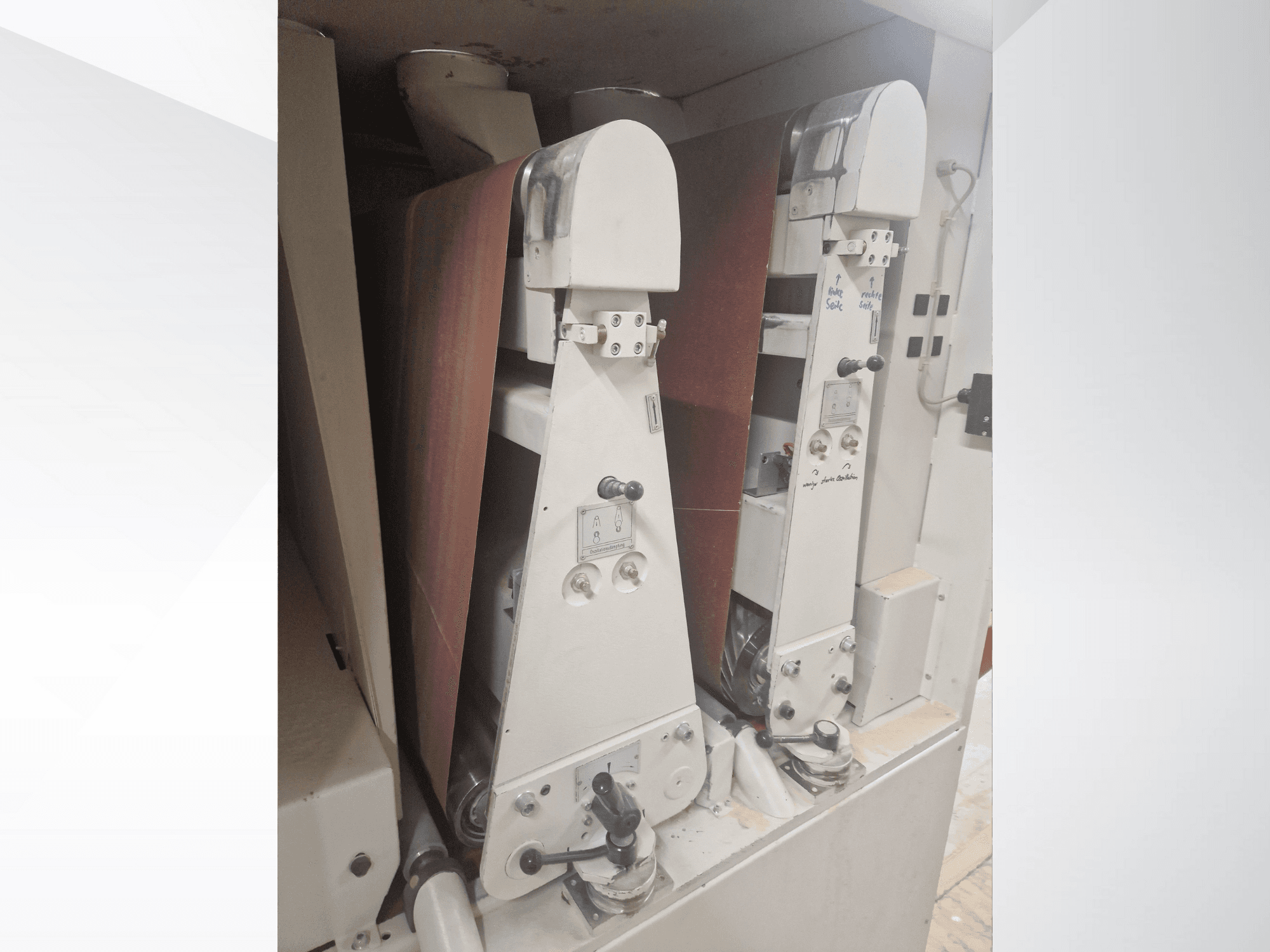 Two industrial sanding machines with red sanding belts, front view, showcasing controls and metallic components.