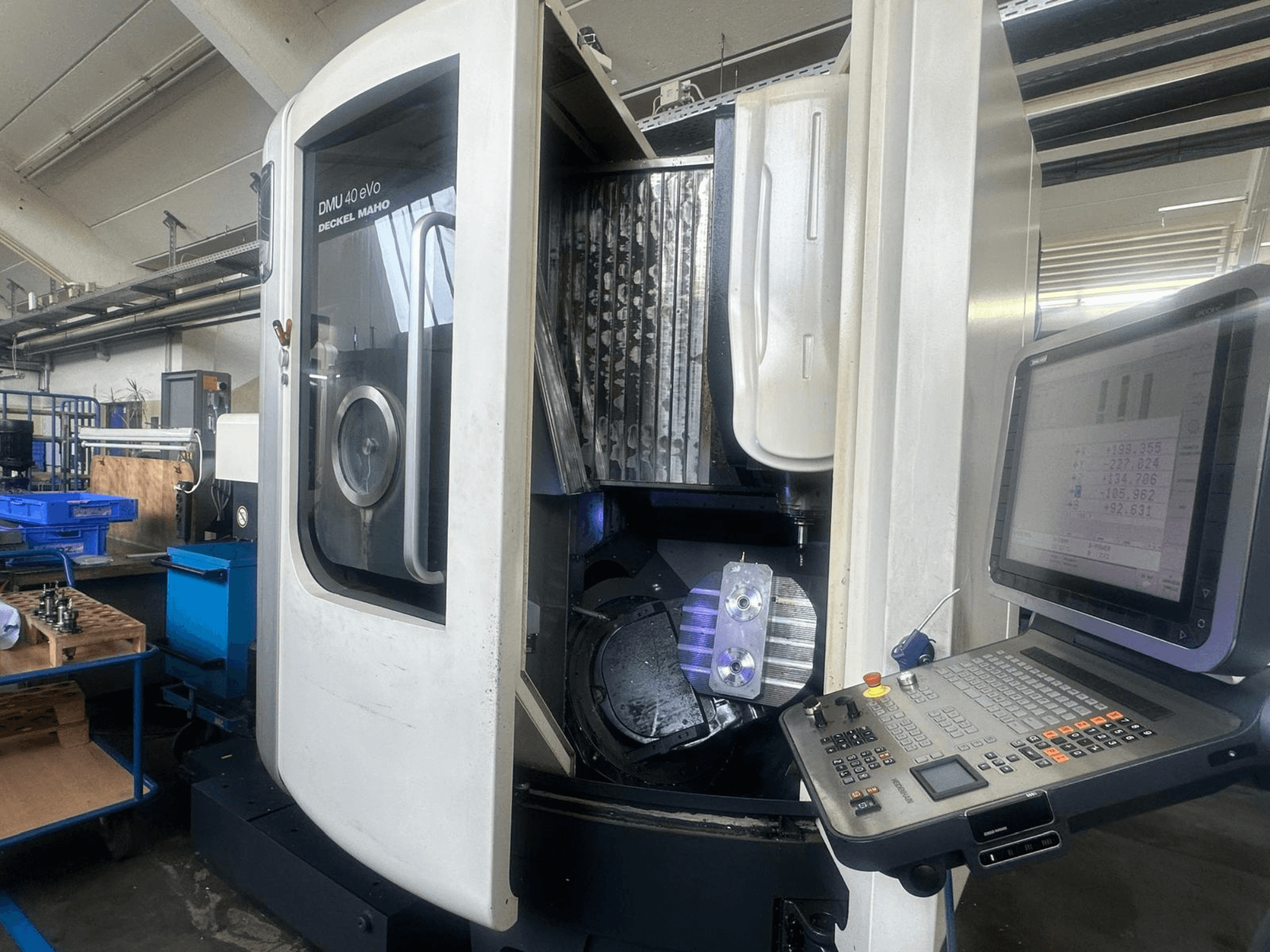 DMU 40 eVo milling machine by Deckel Maho in a workshop, front view, showing control panel and metal piece in the spindle.