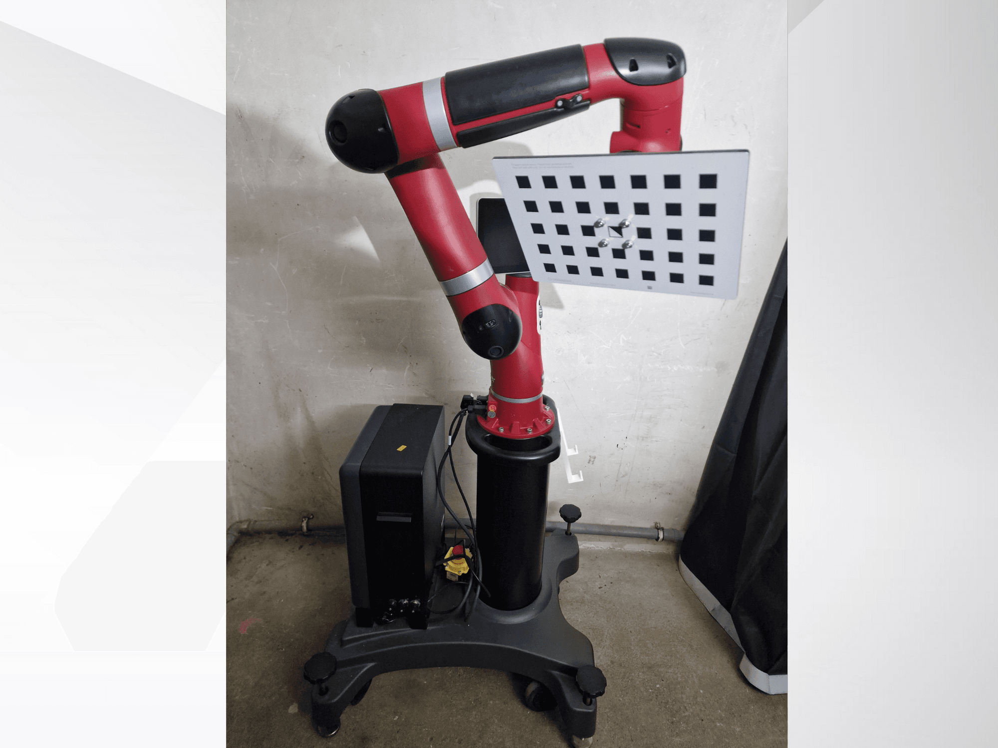 Red robotic arm with a rectangular workspace, equipped with a grid surface and mounted on a black base, side view.