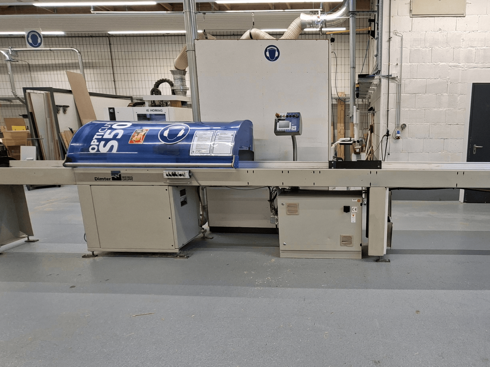 Dimter OptiCut S50 wood cutting machine in side view, featuring a blue housing, control panel, and conveyor belt.