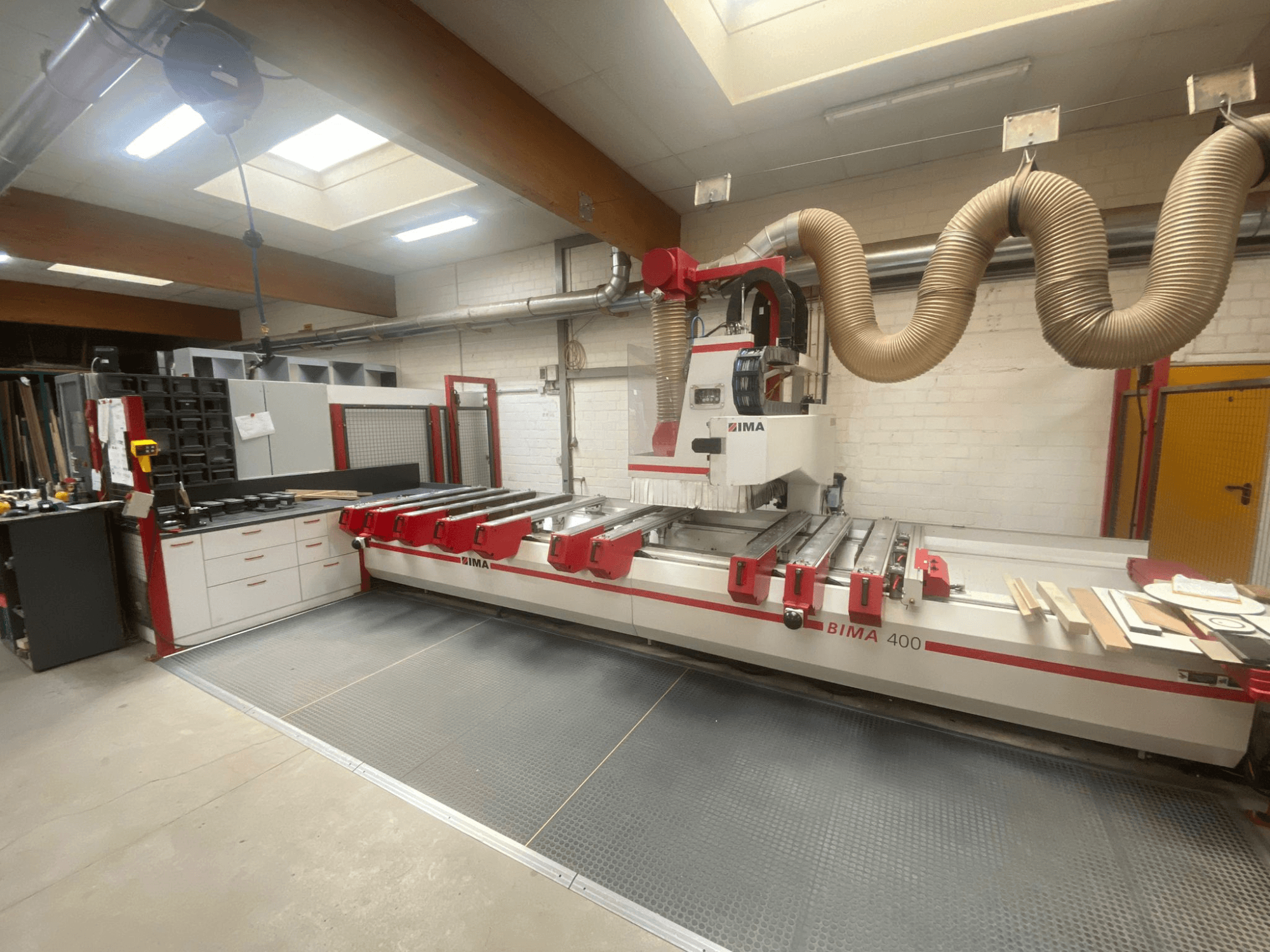 BIMA 400 CNC machine viewed from the front, featuring a red and white design, and a dust extraction system.