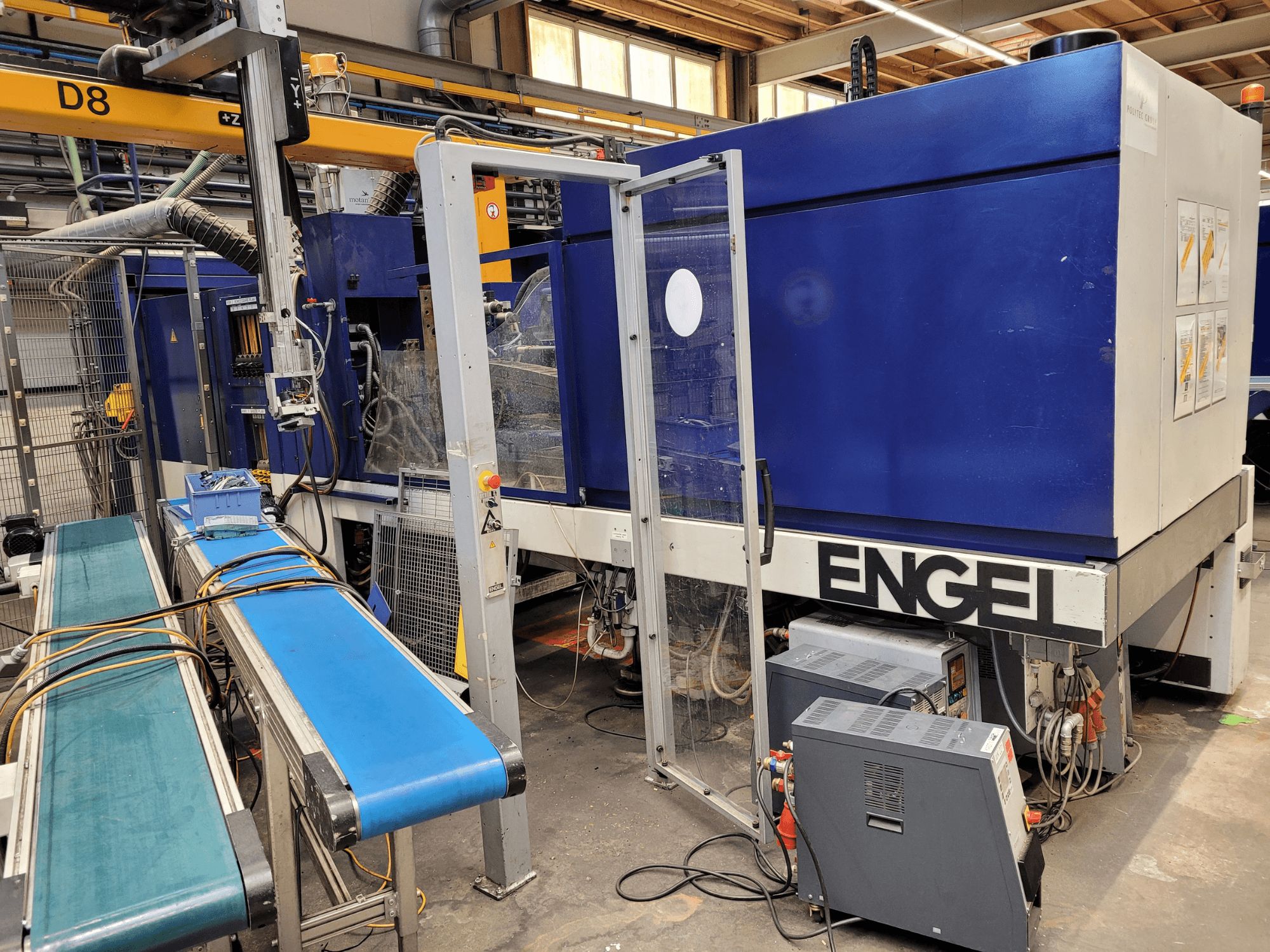 Blue ENGEL machine with a clear safety door, side view, featuring control panel, conveyor belt, and visible electrical connections.