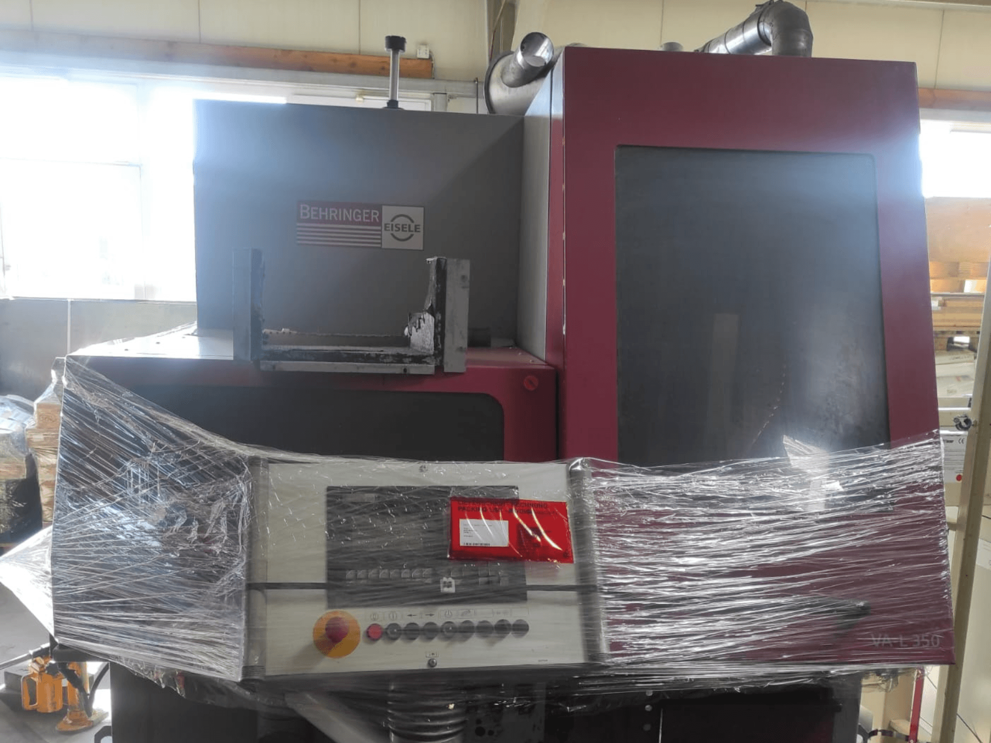 Behringer Eisele VA L 560 machine, front view, wrapped in plastic, with control panel and buttons visible.