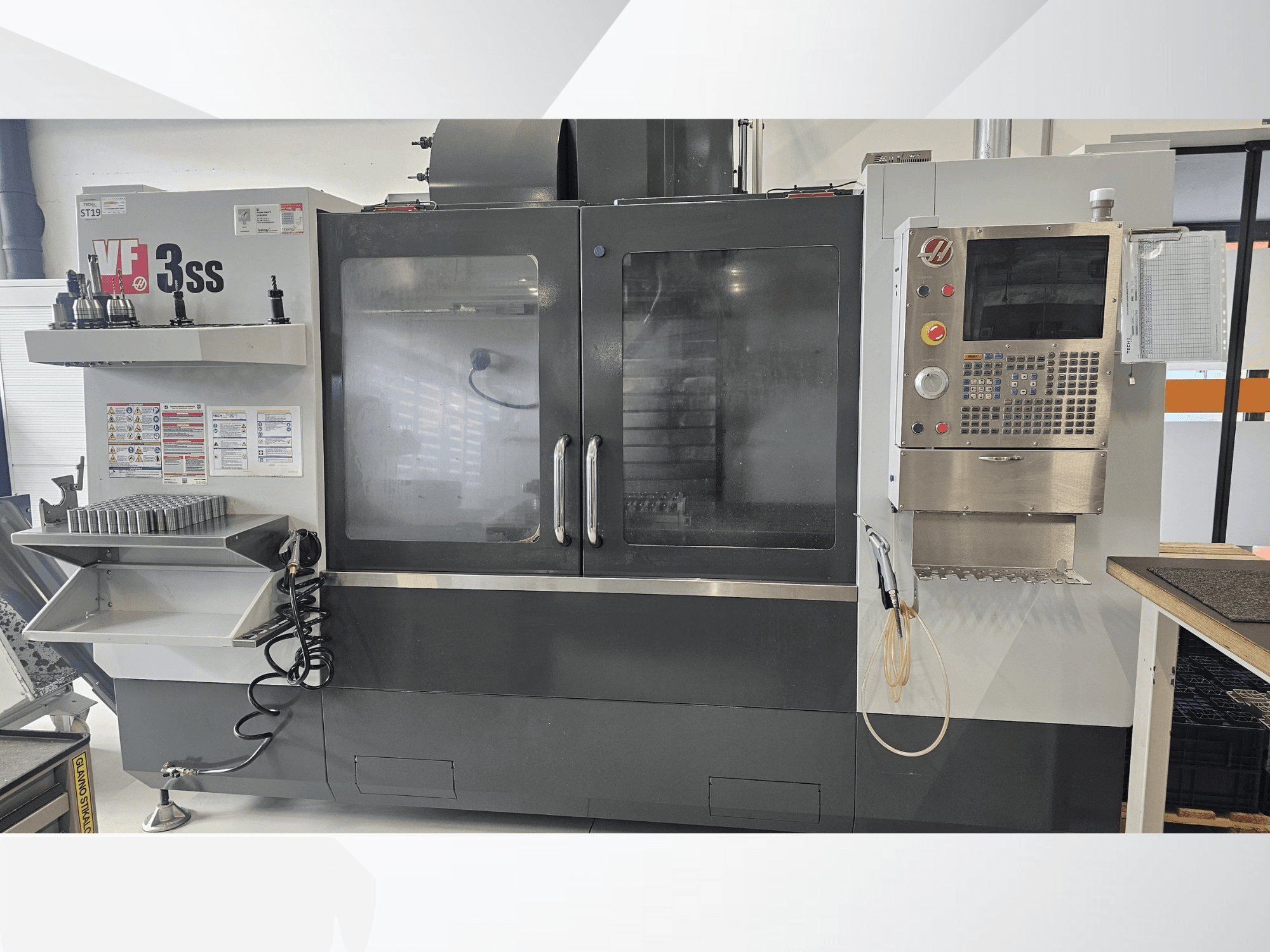 HAAS VF-3SS vertical machining center, front view, featuring control panel, tool rack, and large glass door.